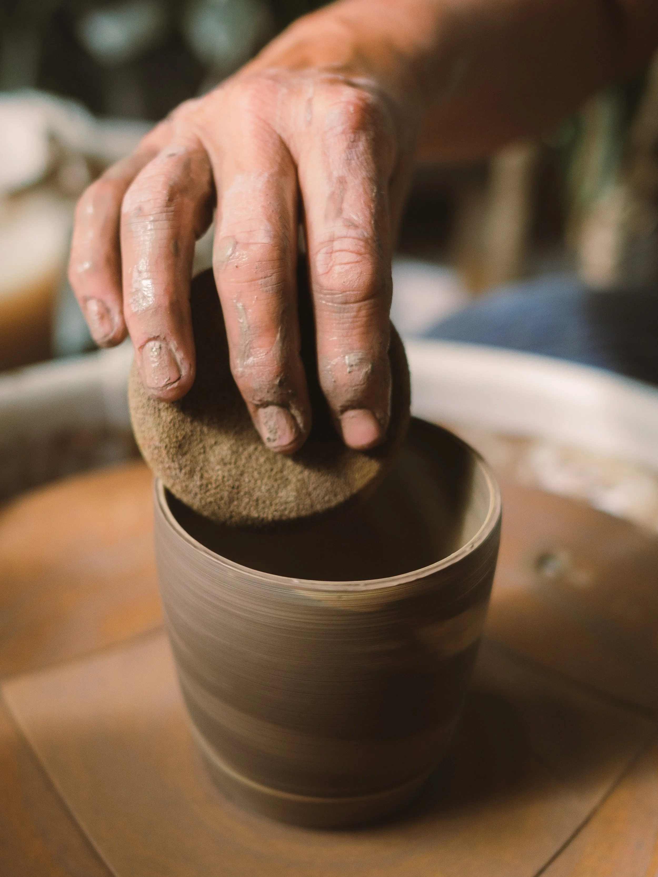 Close-up of a person's hand shaping clay on a pottery wheel.