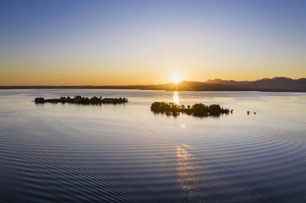 Ein Sonnenuntergang über einem ruhigen See mit kleinen Inseln.