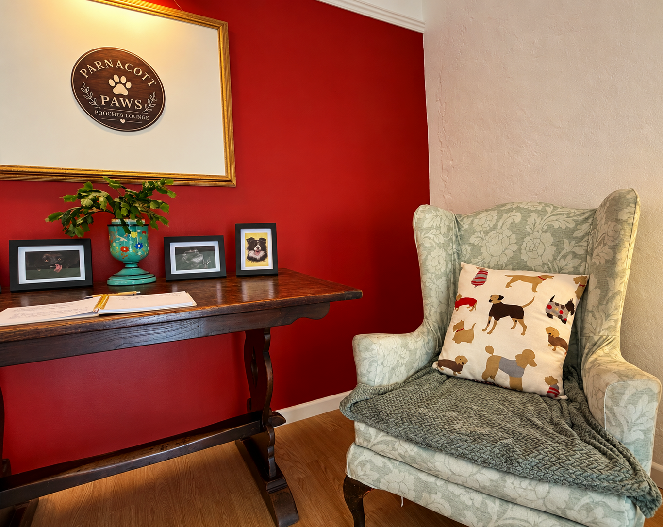 Cozy dog-themed reading nook with a floral armchair, dog-print pillow, patterned throw, framed pet photos, plant, and Parnacott Paws Pooches Lounge sign at Parnacott House & Parnacott Paws.