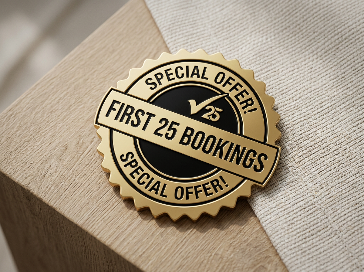 Gold-colored badge with black text that reads 'Special Offer! First 25 Bookings' placed on a wooden surface with a beige cloth next to it.