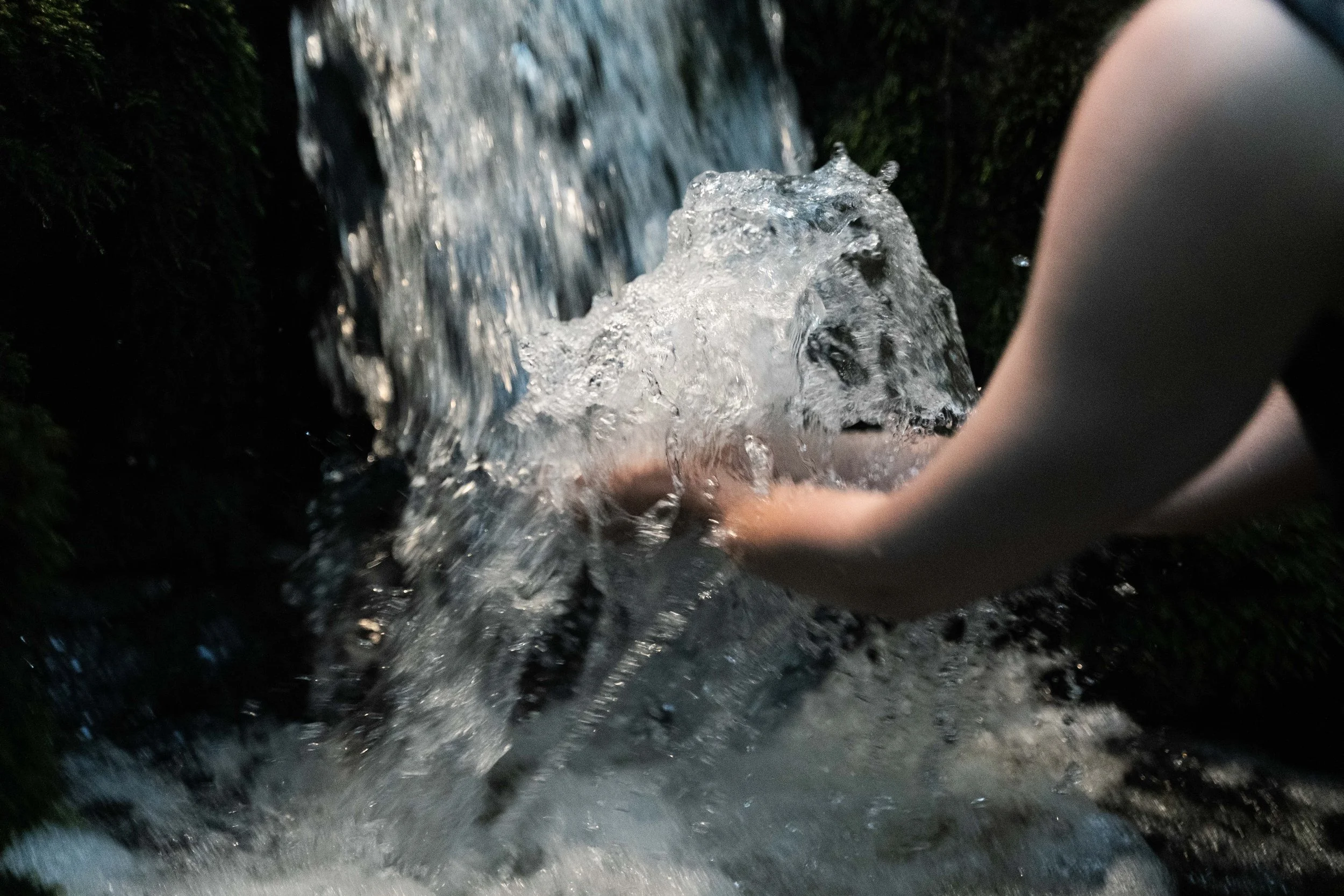 Close-up of water flowing over rocks in a small waterfall in a natural outdoor setting.