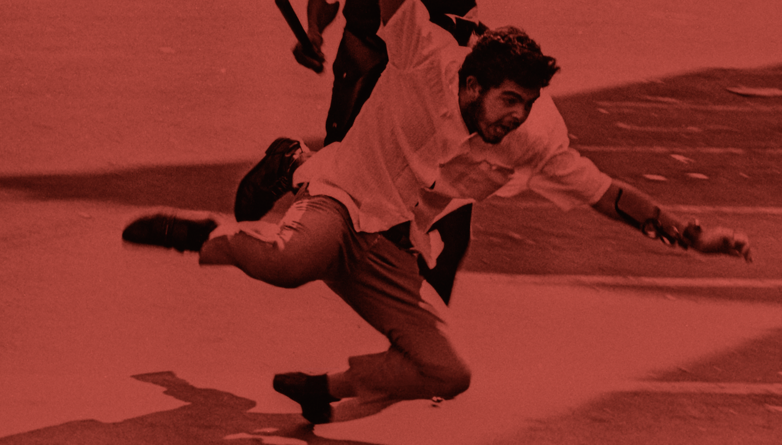 A man is falling forward on a red surface, with one arm extended and a joyful expression on his face, in a dynamic pose.