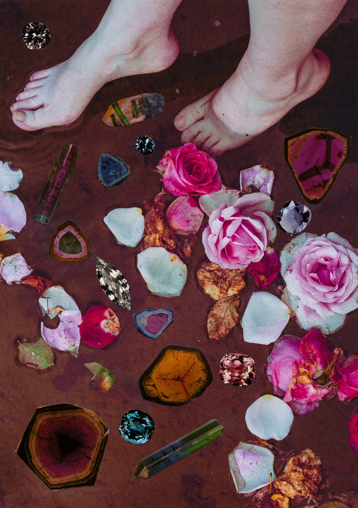 A photo of two bare feet standing among pink and white rose petals, surrounded by various colorful gemstones on a dark surface.