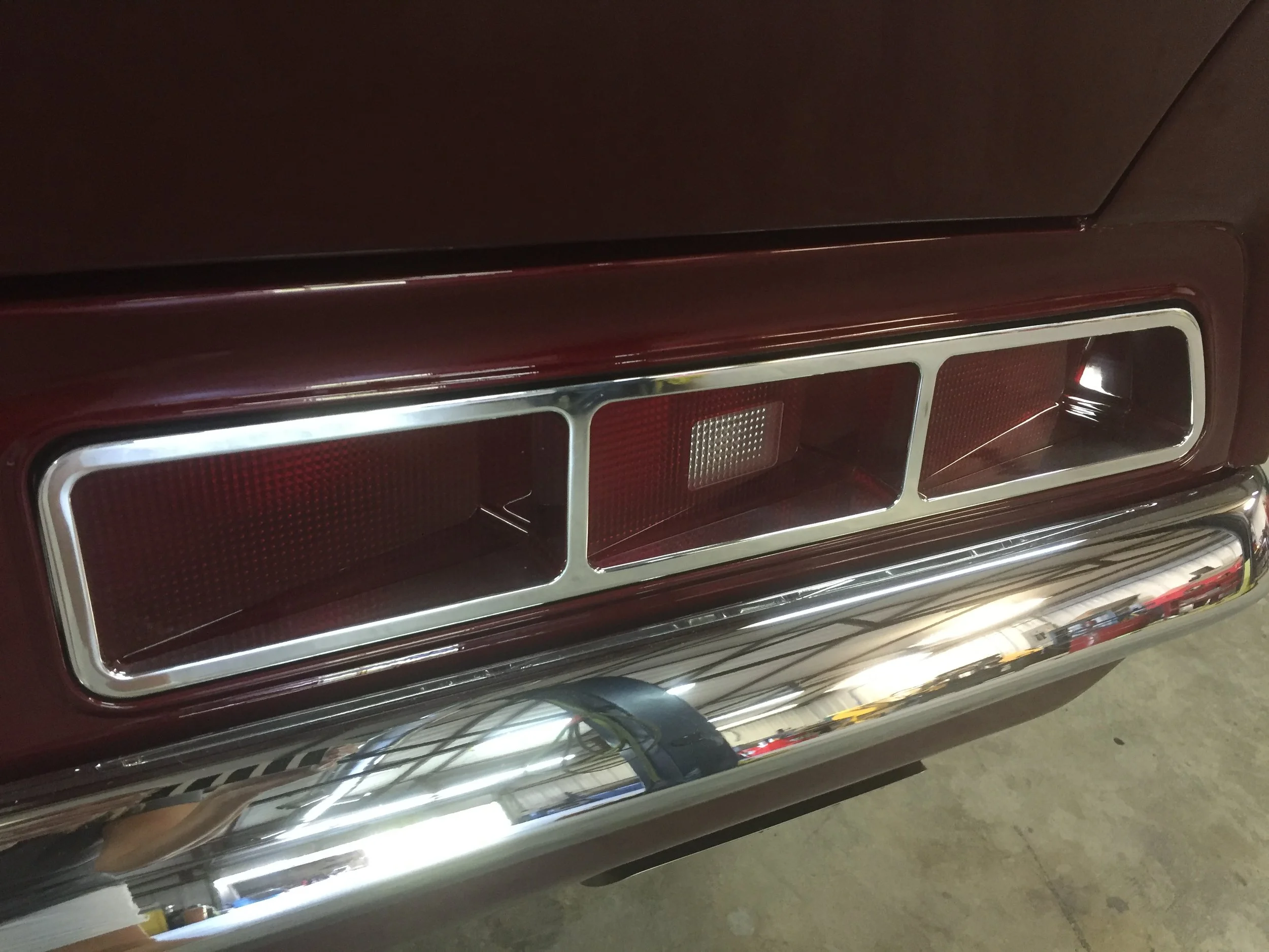 Close-up of a vehicle front grille with red and silver accents, reflecting the surrounding environment.