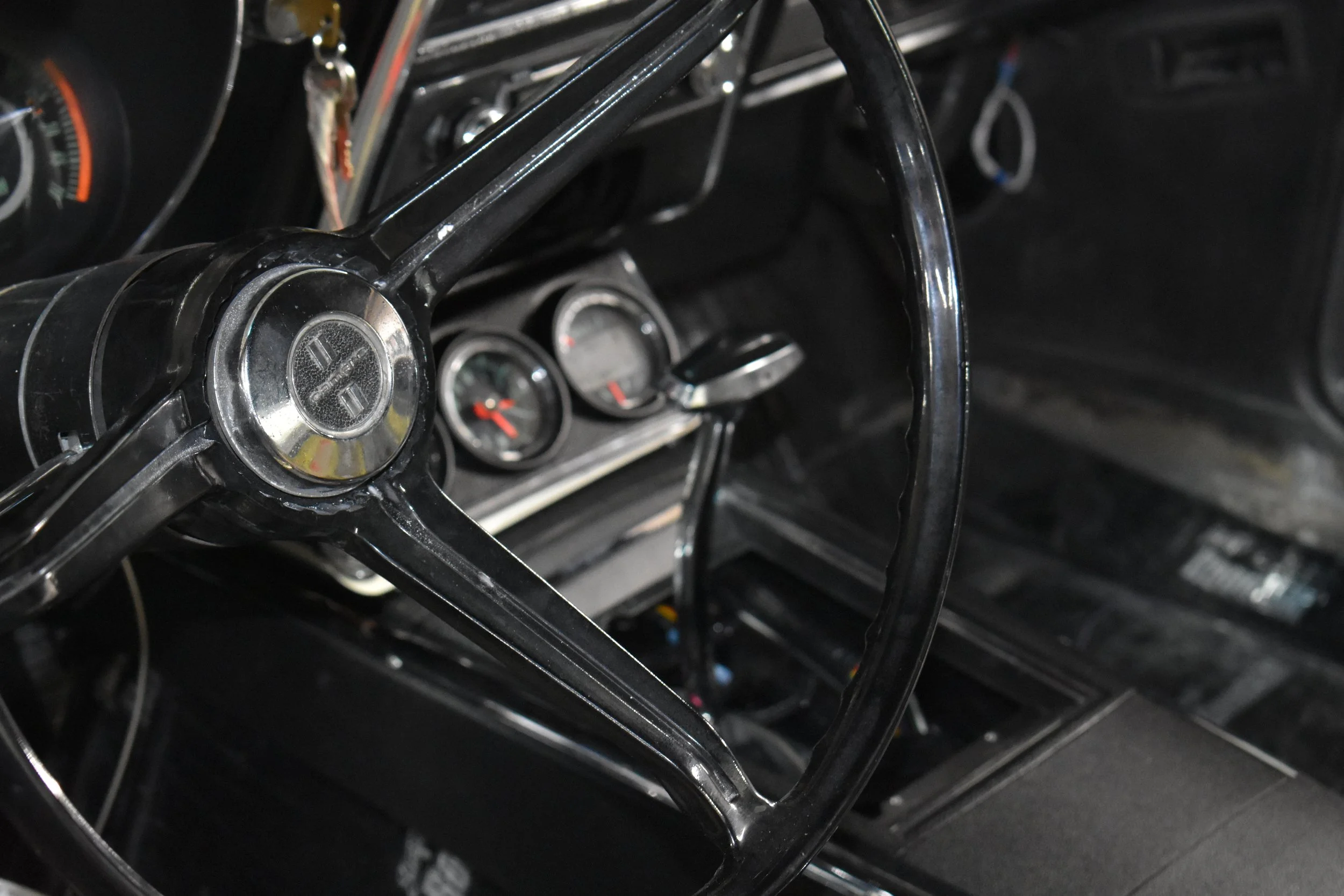 Close-up of a vintage car's steering wheel and dashboard gauges.
