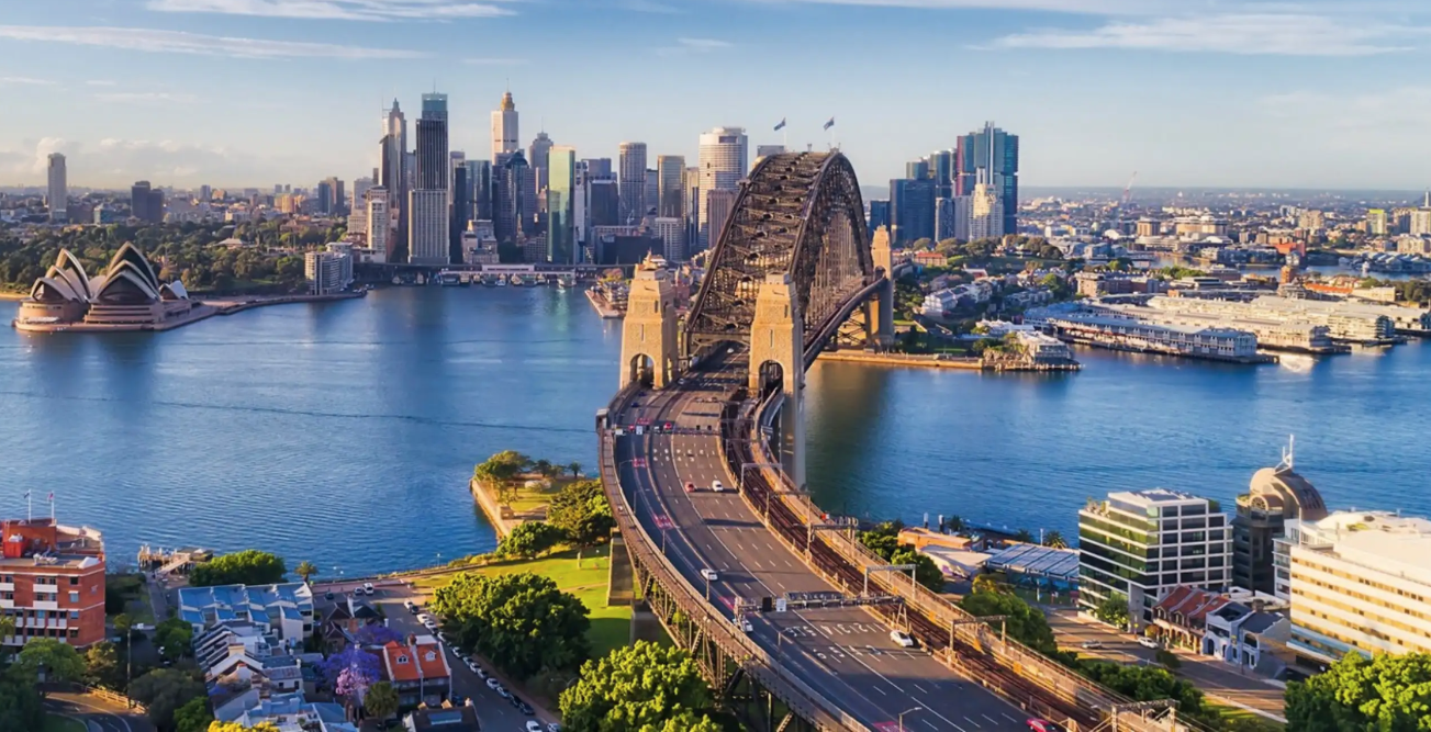 Aerial view of Sydney Harbour Bridge and Sydney Opera House with city skyline in the background.