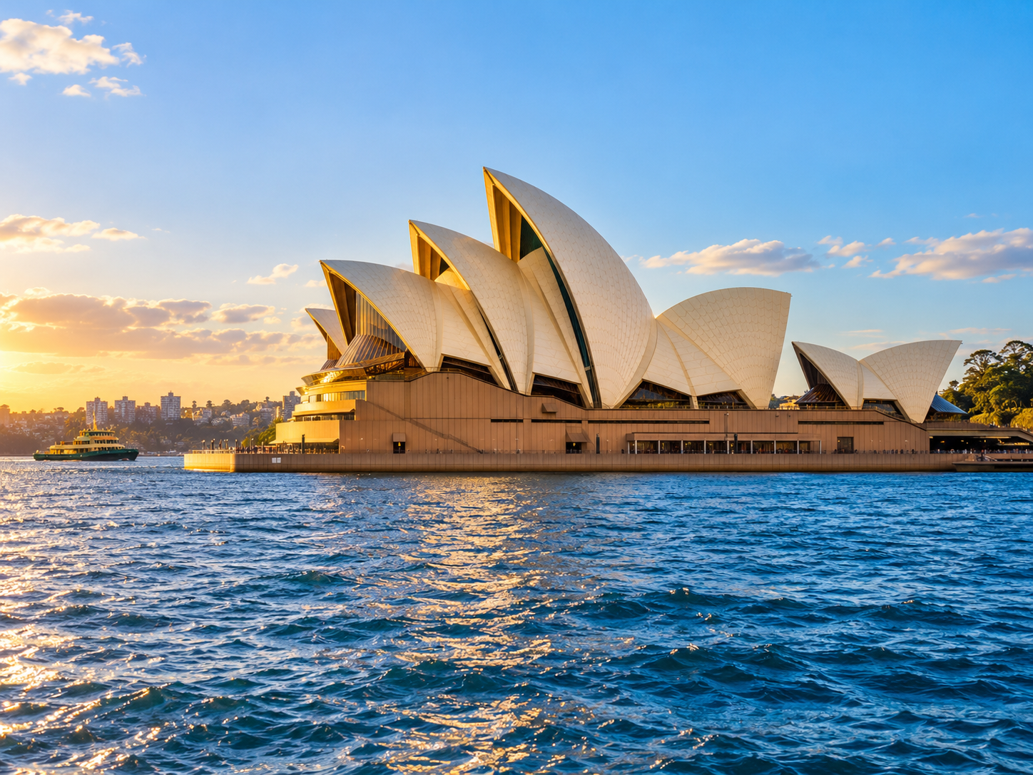 Sydney Opera House overlooking Sydney Harbour, with sunlit sails and sparkling blue water.