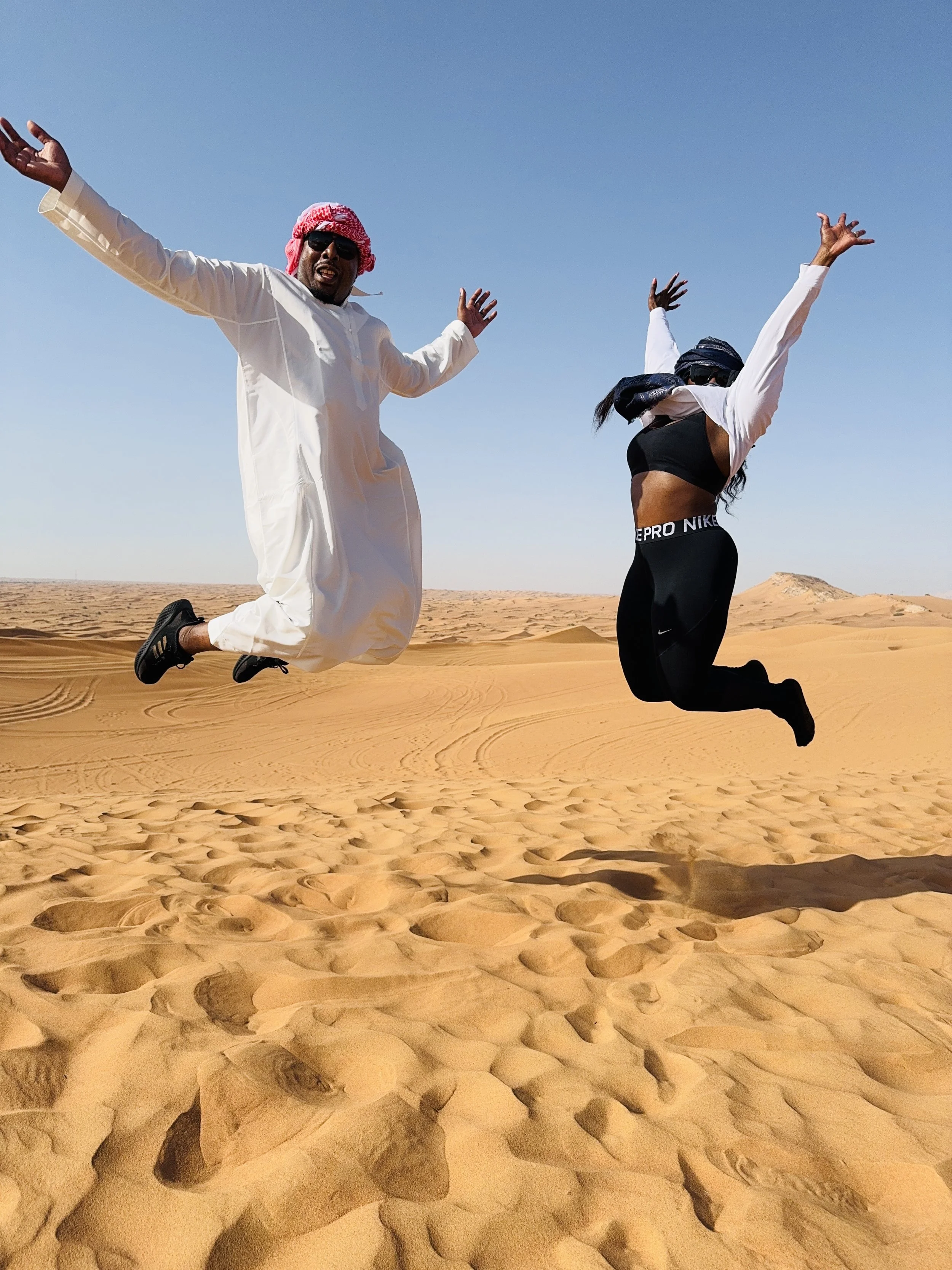 Couple jumping high in the Dubai desert