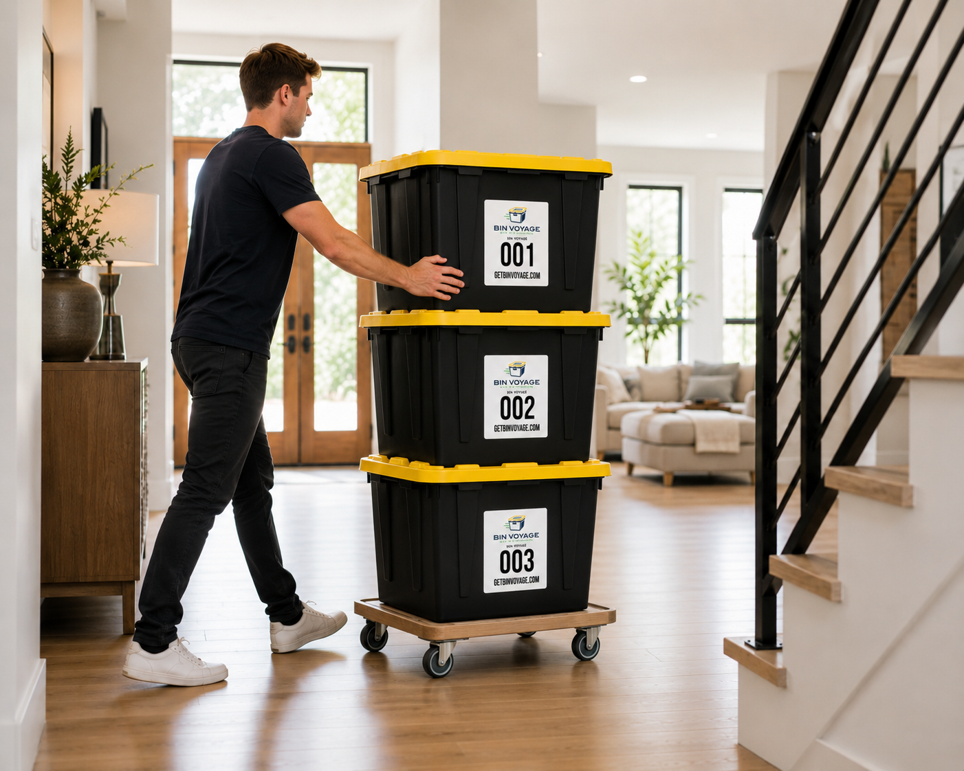 A man stacking three large black storage bins with yellow lids, labeled with numbers 001, 002, and 003, inside a modern home.