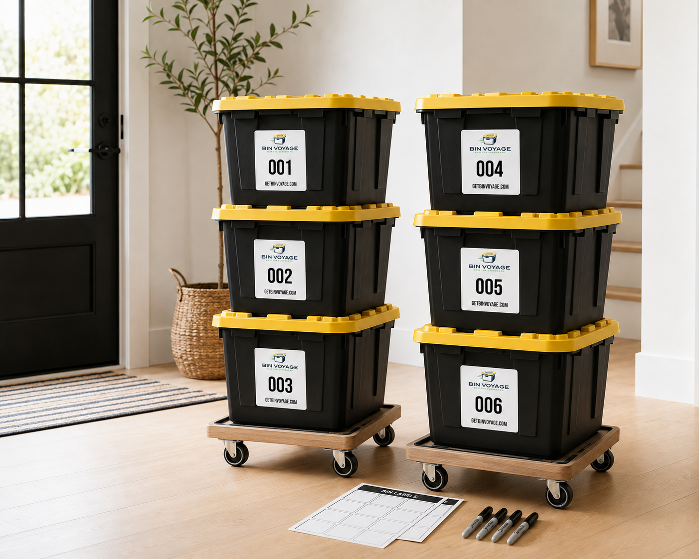 Four black storage bins with yellow lids, labeled with numbers 001 to 006 and the logo 'Bin Voyage', stacked on wheeled wooden trolleys inside a room near a staircase and a door.