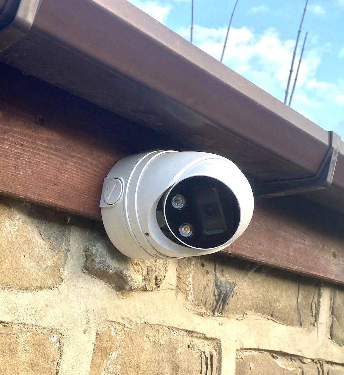 Security camera mounted on a brick wall, pointing downward.