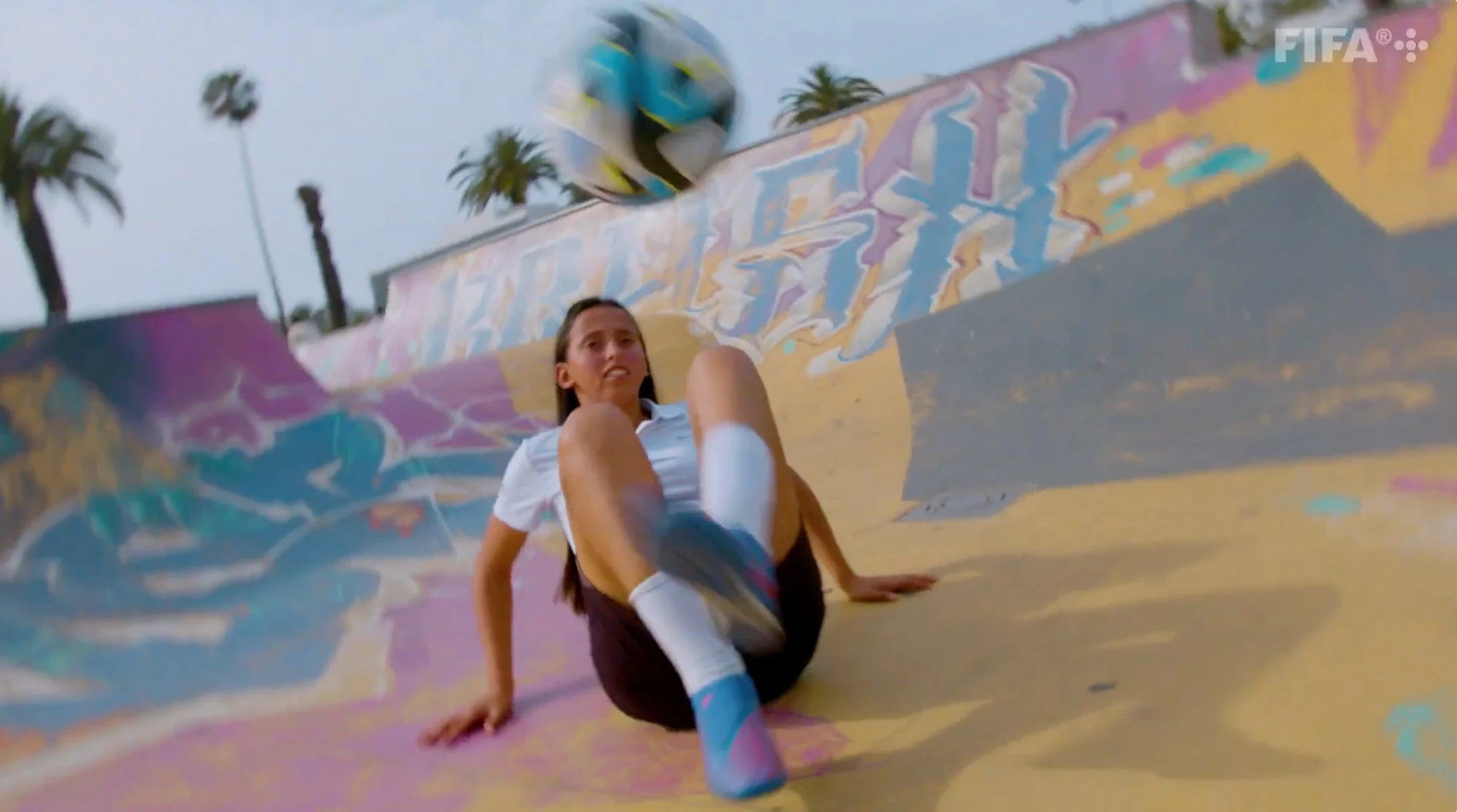 Fatima Ezzahra sitting on a graffiti-covered skate ramp under palm trees, still from the FIFA+ film Sheroes by CTRL Pictures