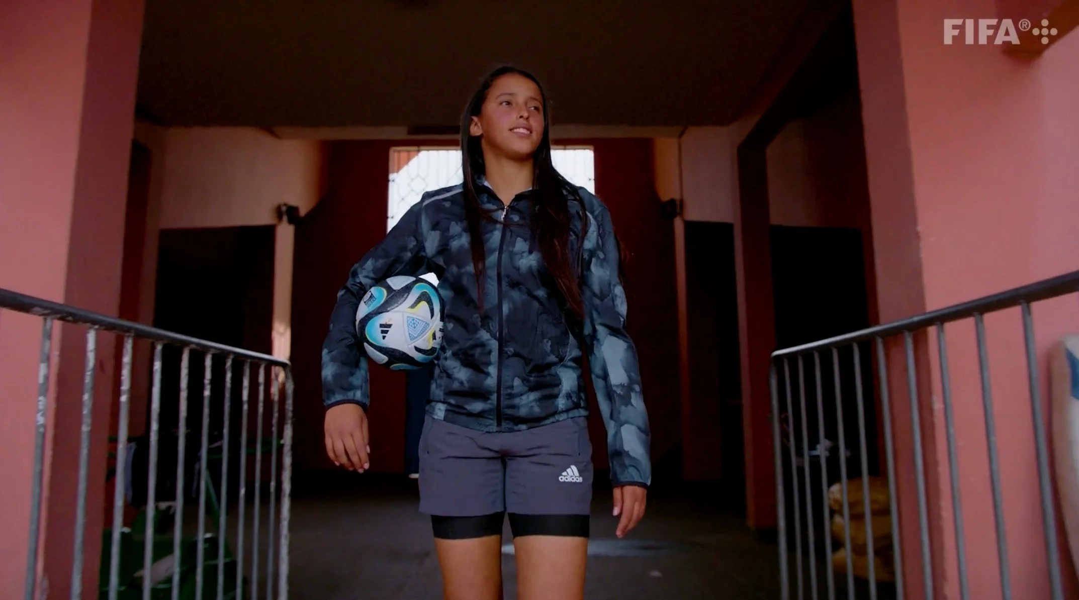 Footballer Fatima Ezzahra walking down a stairway holding a football in the FIFA+ film Sheroes