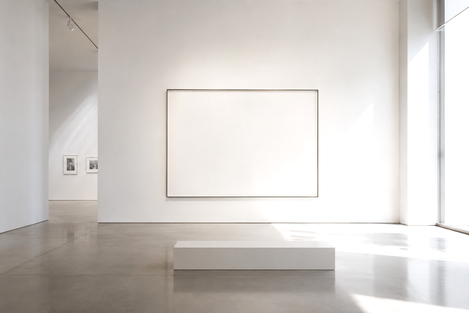 Minimalist art gallery with a large blank white canvas on the wall, a white bench in front, and smaller framed artworks on the adjacent wall, with natural light coming through windows.
