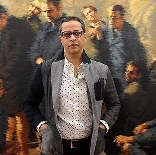A man standing in front of a mural with multiple figures in the background.