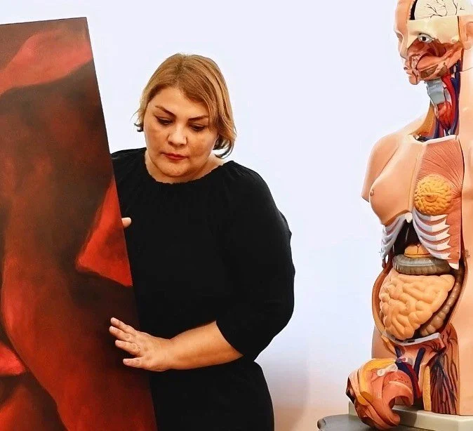 A woman in a black sweater examining a large anatomical model in a science classroom or museum setting.