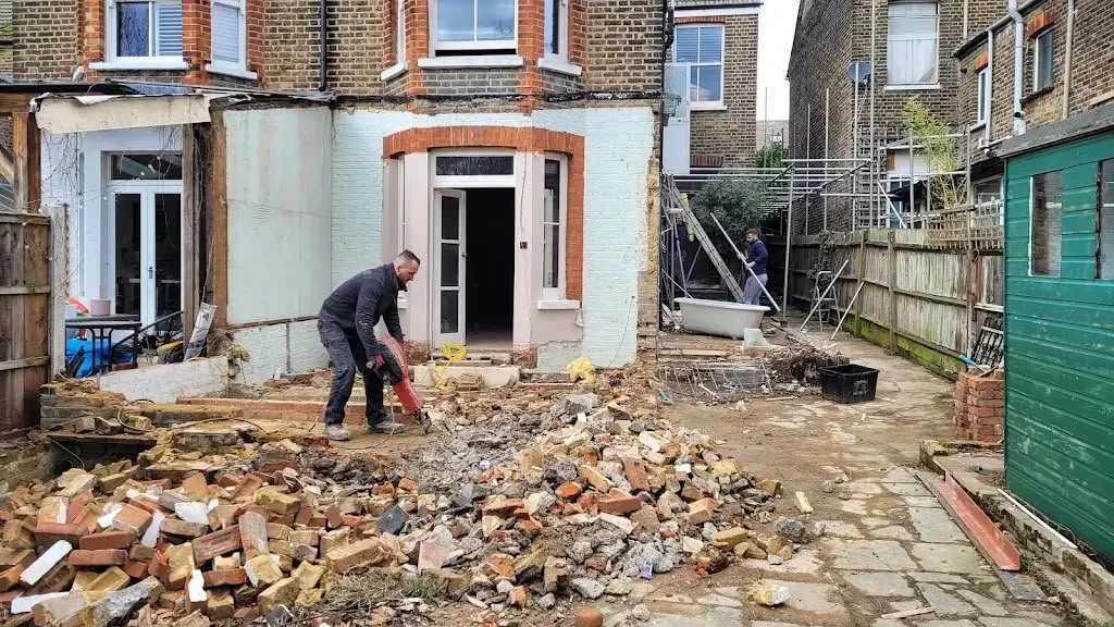 People working on a backyard renovation, tearing up concrete and bricks.
