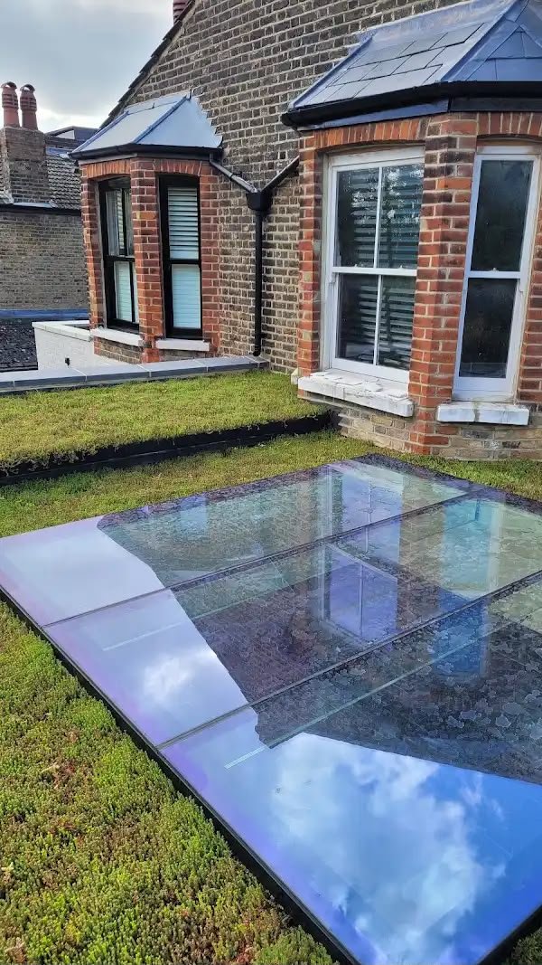 Reflective glass panels installed on a rooftop garden in front of brick apartment buildings with bay windows.