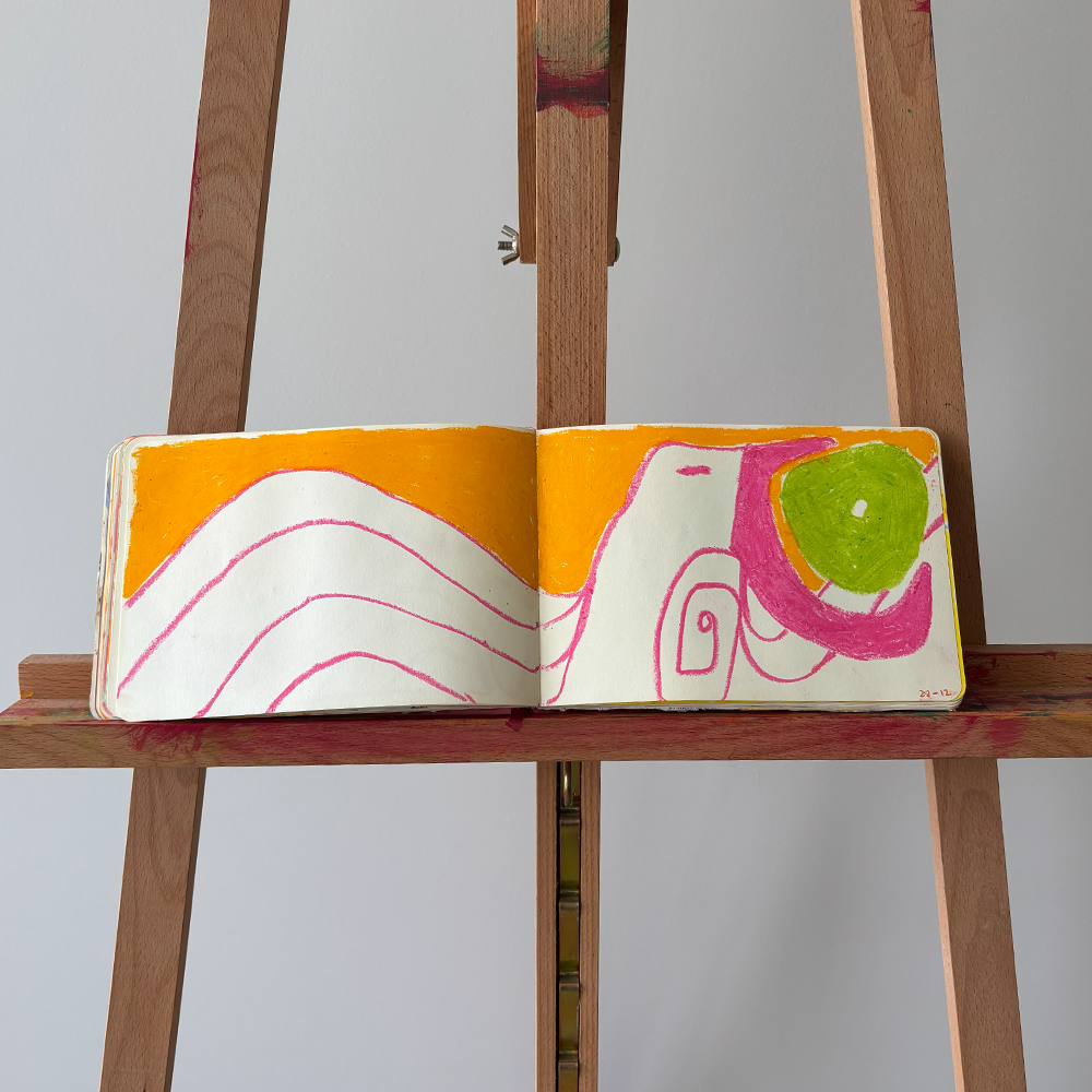 Desenho colorido de formas abstratas em uma página de caderno apoiada em um cavalete de madeira