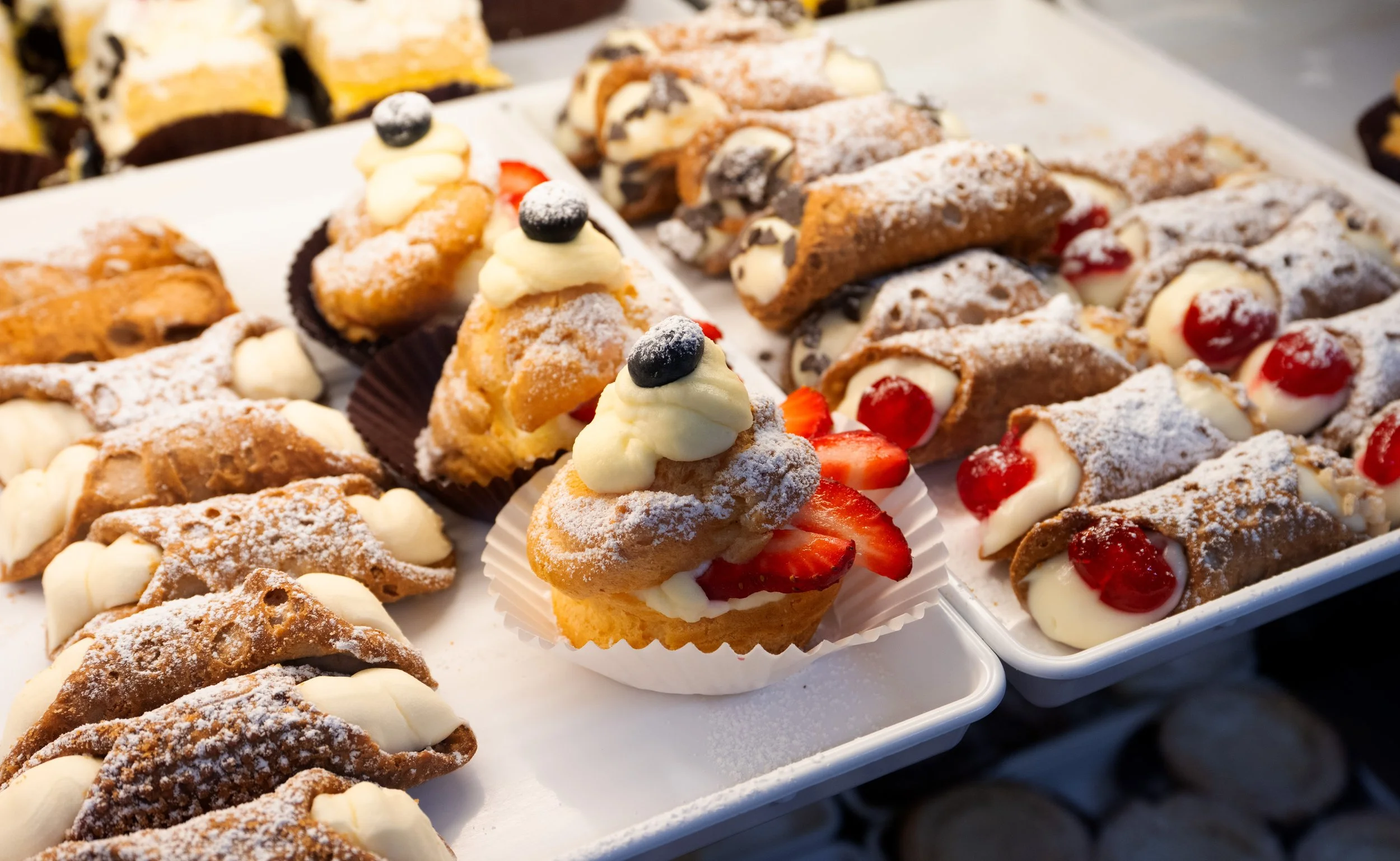 Verschiedene belgische Waffeln mit verschiedenen Toppings, darunter Sahne, Früchte und Schokolade, auf einem Verkaufsstand.