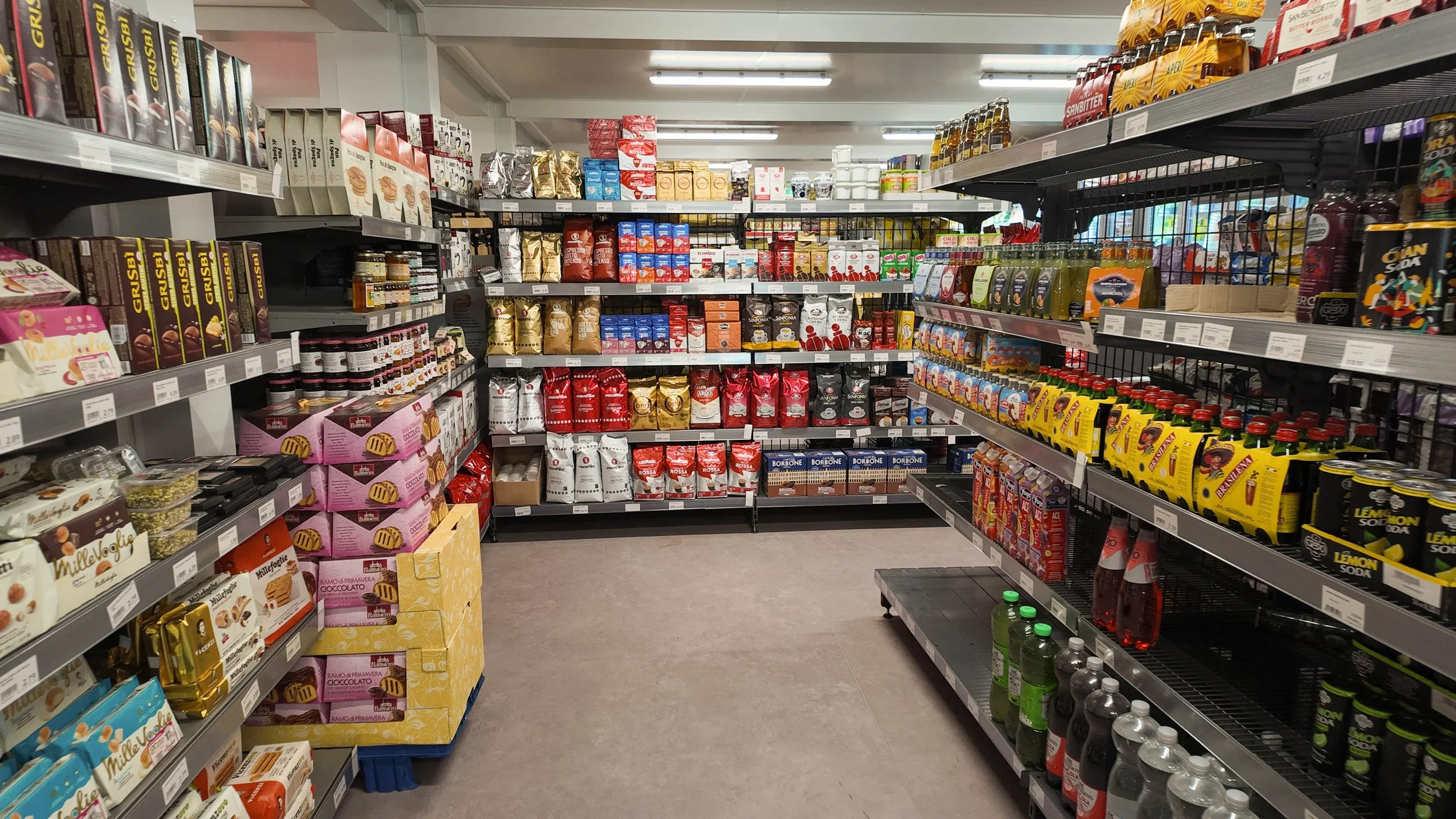 Regal mit verschiedenen Süßigkeiten, Keksen, Getränken und Lebensmitteln im Supermarkt.
