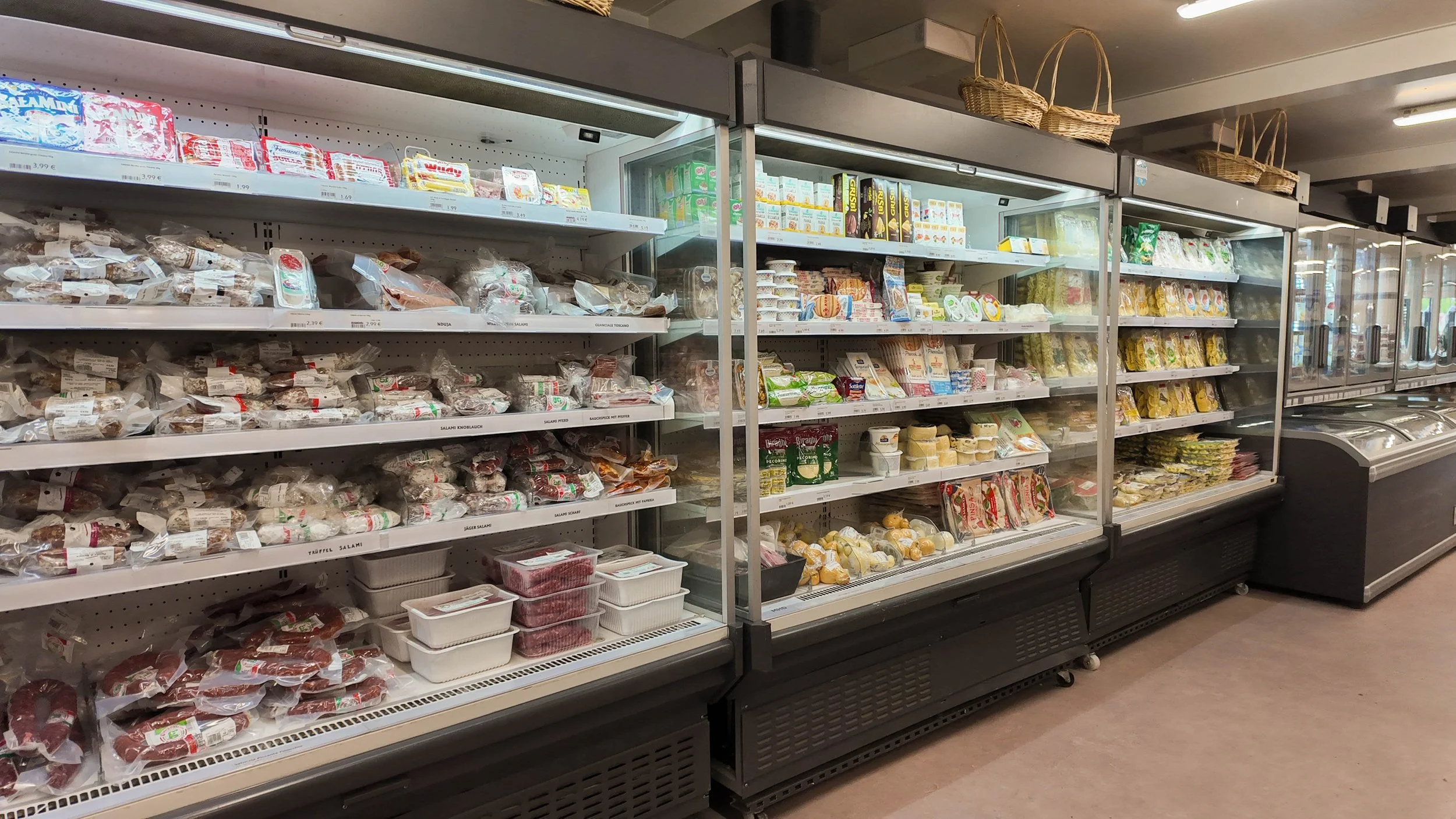 Blick auf die Kühlregale in einem Supermarkt mit verschiedenen Fleisch- und Käseprodukten.
