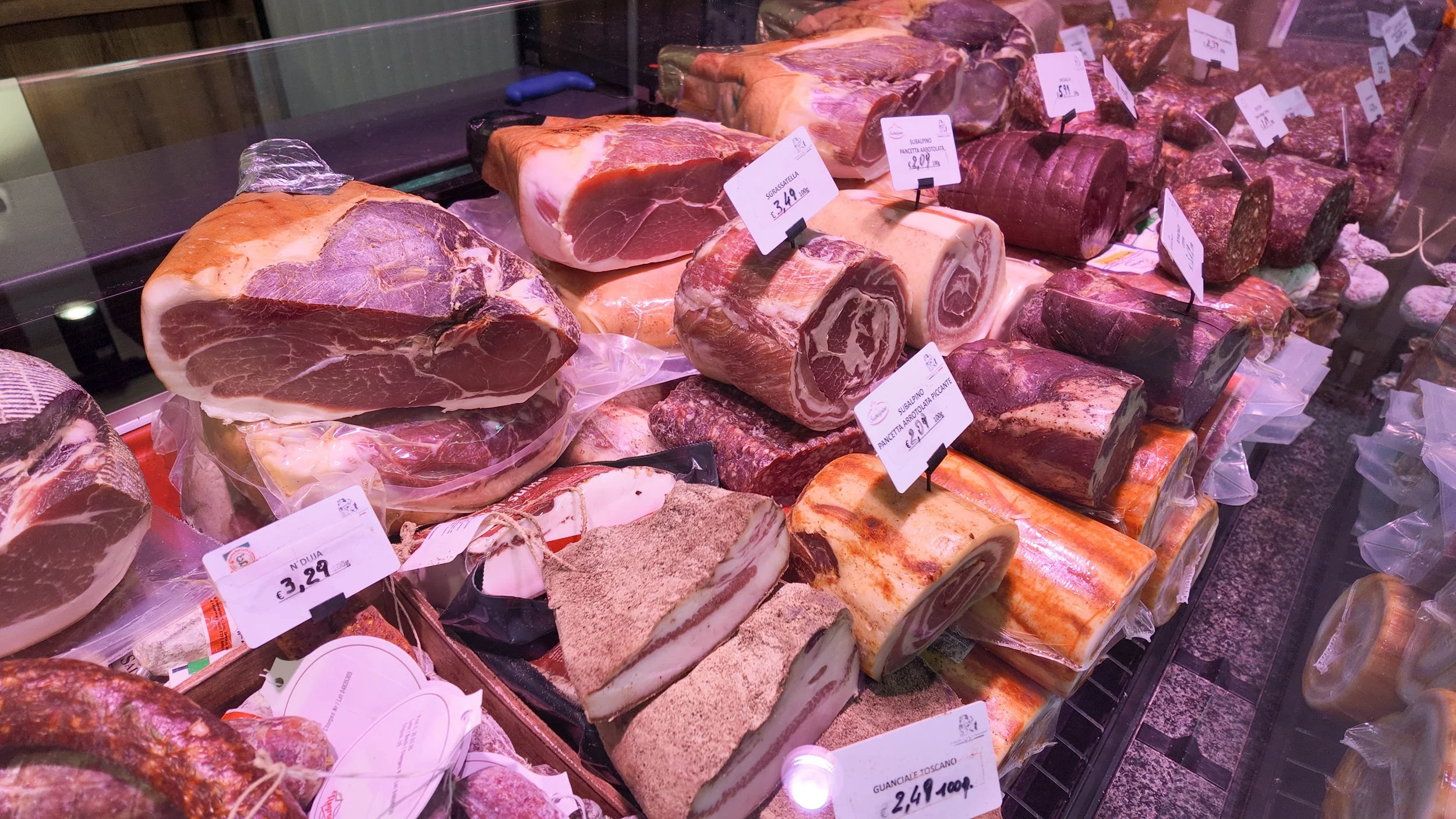 Verschiedene Arten von Fleisch und Wurstwaren in einer Fleischtheke, mit Preisschildern in einem Supermarkt