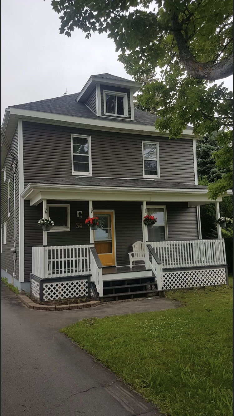 Renovated grey house with a white porch and yellow front door.