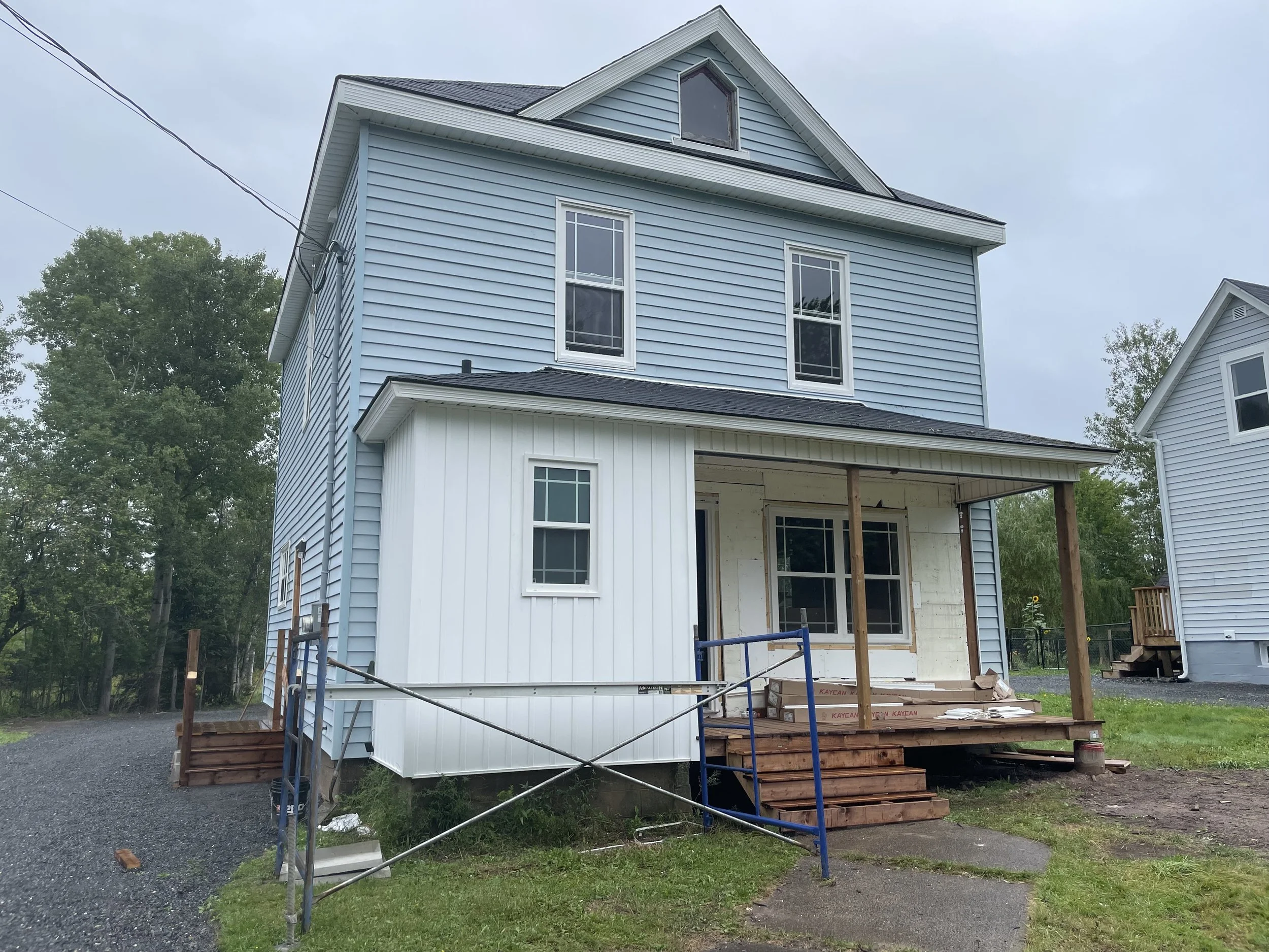 Light blue house undergoing exterior renovation in Westville, Nova Scotia.