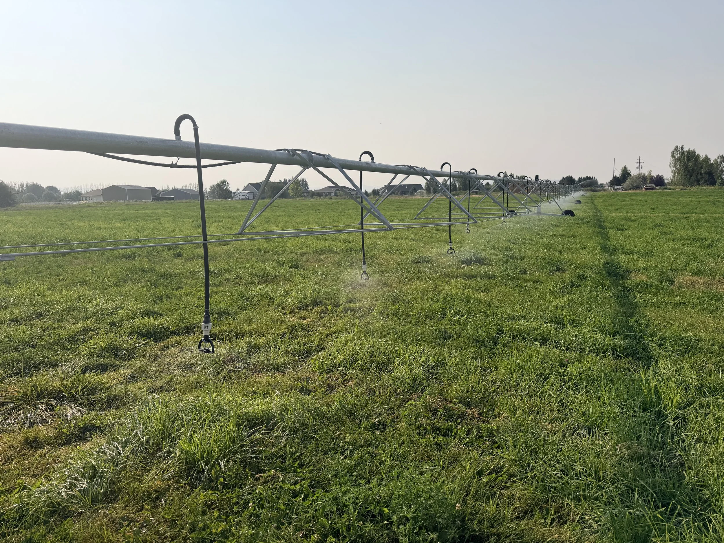 A close-up view of a large irrigation sprinkler system spraying water across a green field.