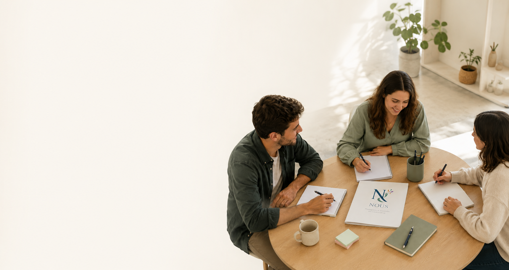 Tres personas en una reunión de trabajo sentadas alrededor de una mesa de madera, compartiendo ideas y tomando notas.