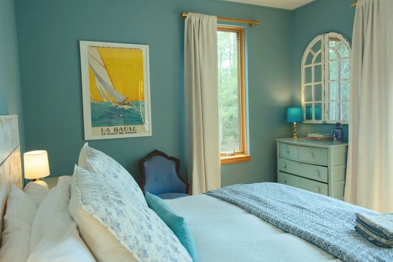 A blue guest-house bedroom with a floral quilt and soft pillows