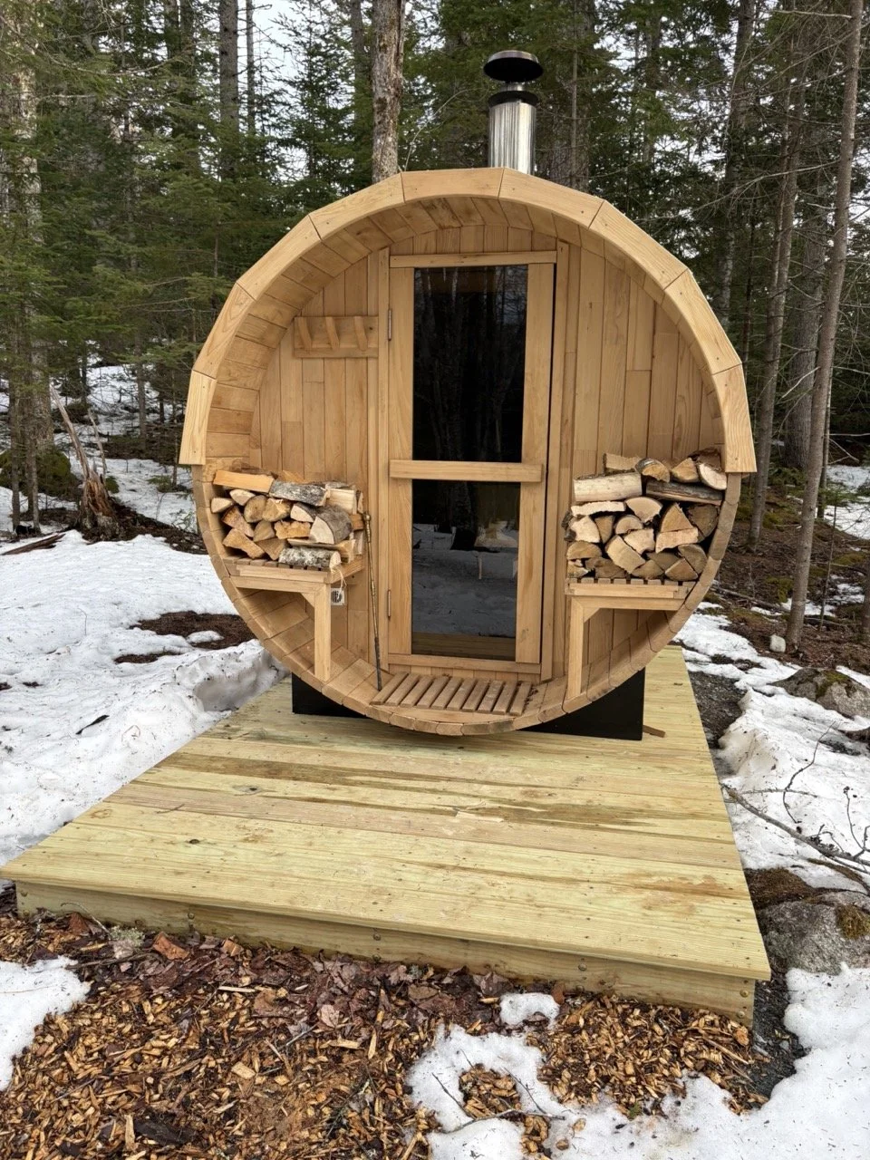 The wood-fired barrel sauna in the snowy woods at The Pond