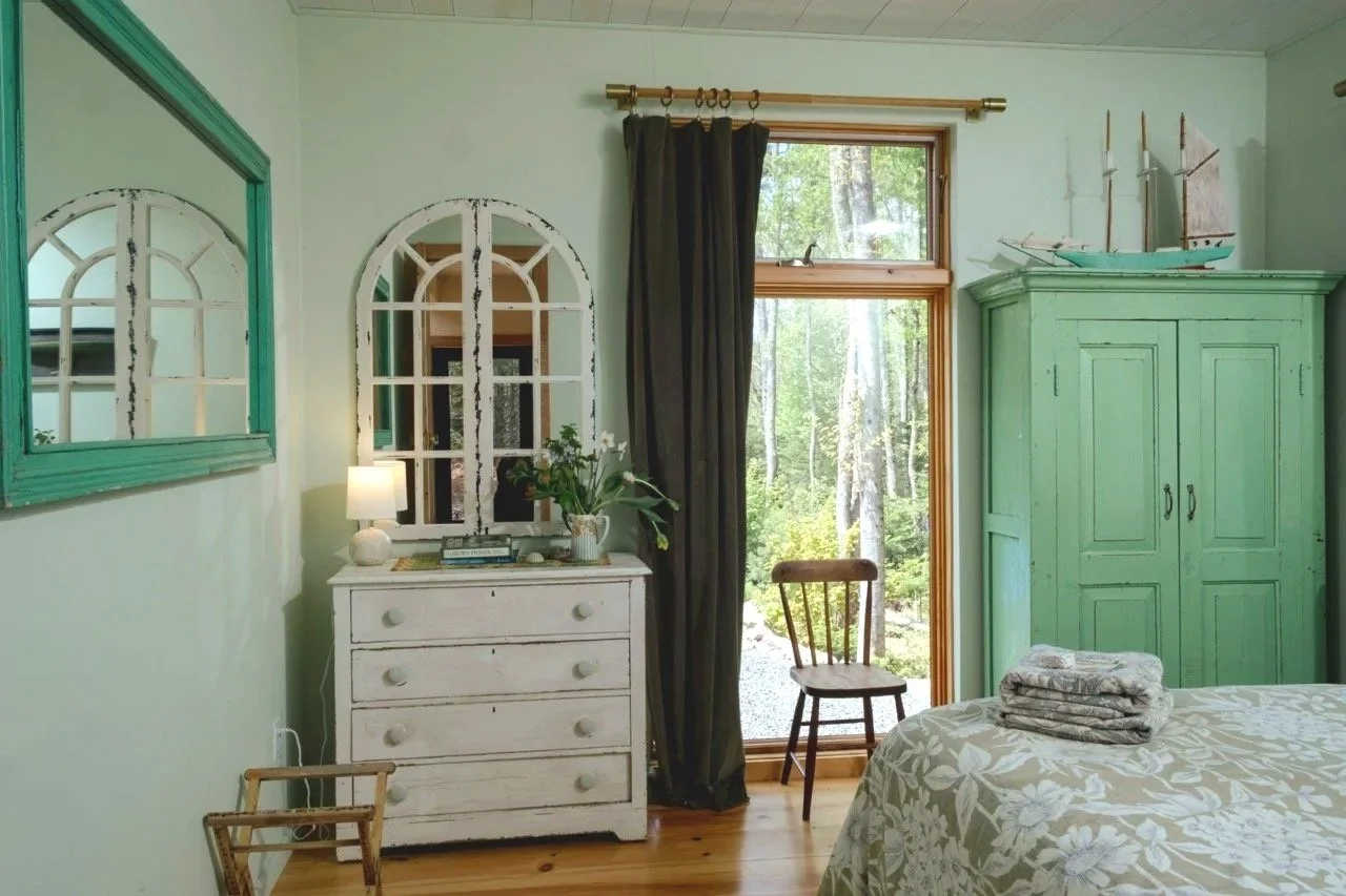 A guest-house bedroom with green furnishings and woodland views