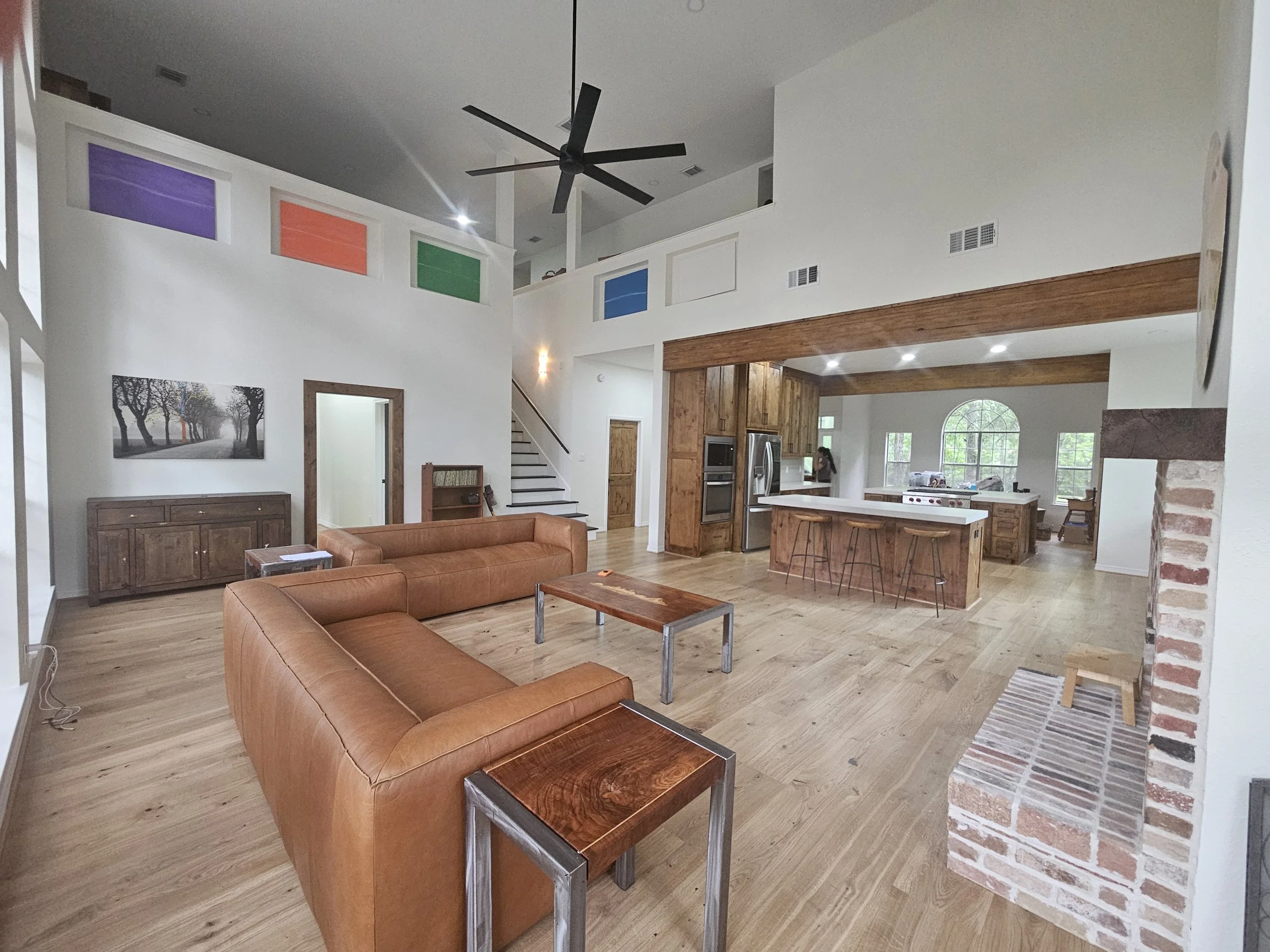 Custom Construction with Open-concept living room and kitchen with leather sofas, wooden cabinets, and colorful wall art.