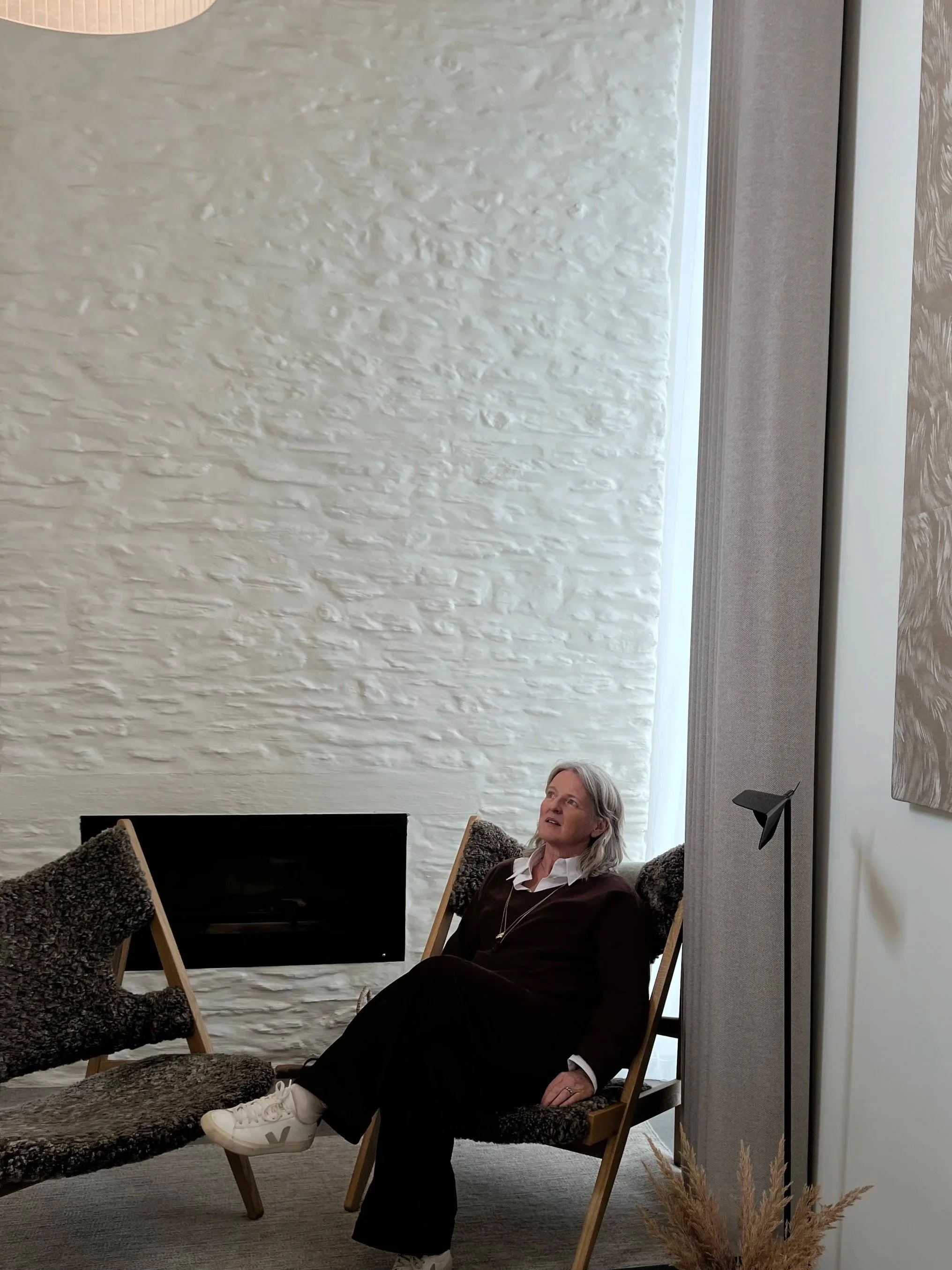 Dr Jo Black is sat looking into the distance pondering and looking analytical, she has a soft expression and is wearing smart garments