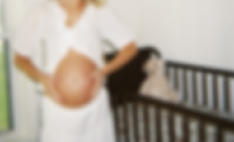 A nurse holding a newborn baby in a hospital room.