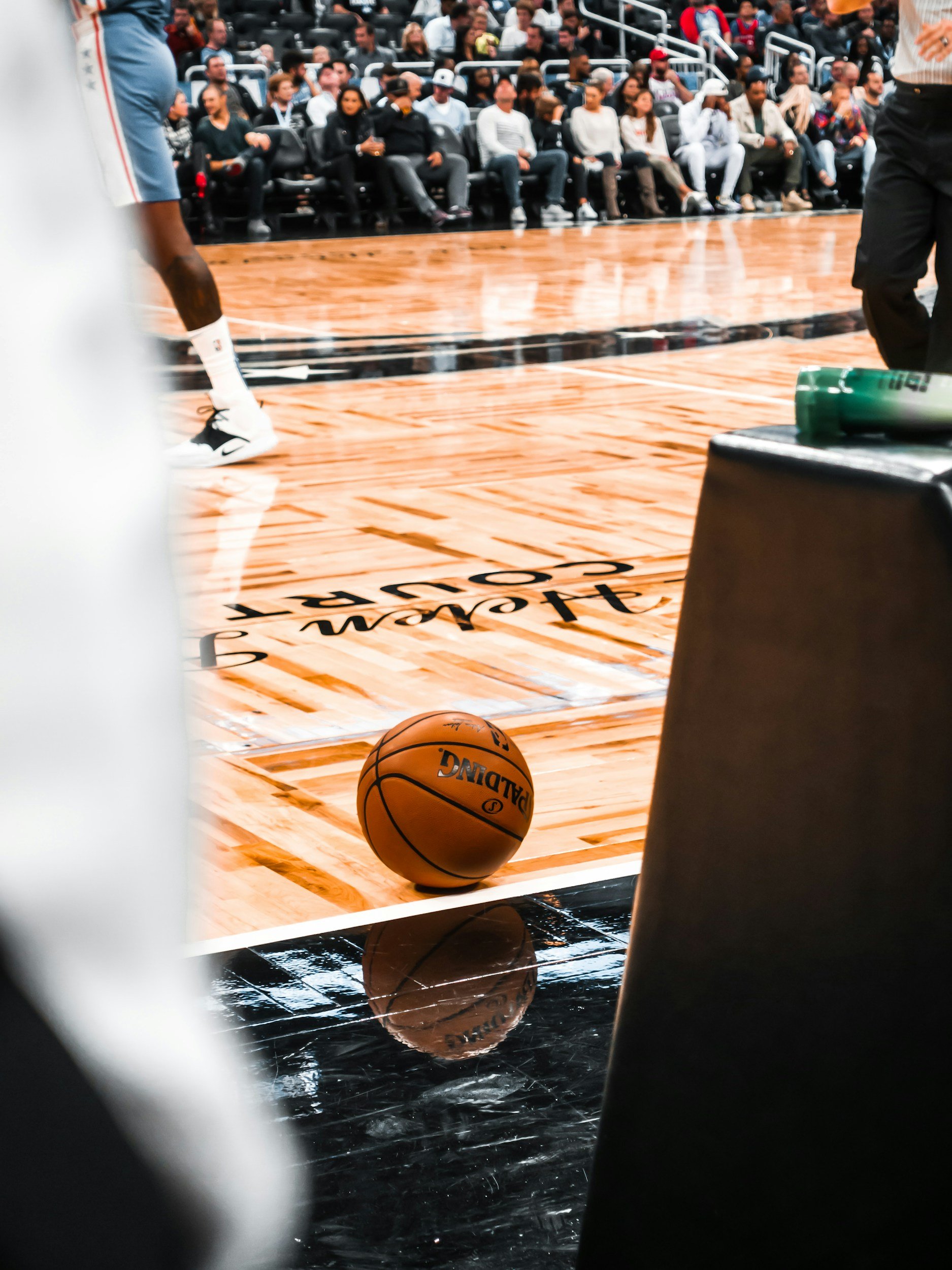 Basketball court with a basketball on the floor and spectators seated in the stands.