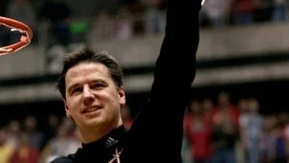 Larry Eustachy celebrating with an arm raised in a public setting, smiling.