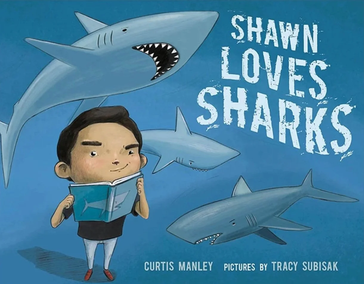 Children's book cover titled 'Shawn Loves Sharks' shows a boy holding a book with a shark on it, surrounded by three illustrated sharks, with the author Curtis Manley and illustrator Tracy Subisak credited.