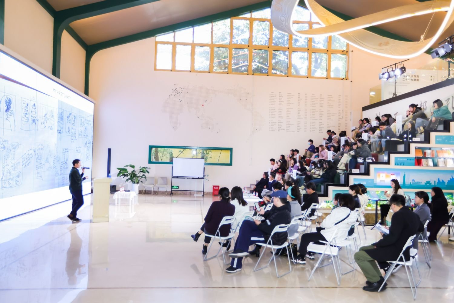 Tracy Subisak presenting illustrations on a large screen to an audience in a lecture hall.