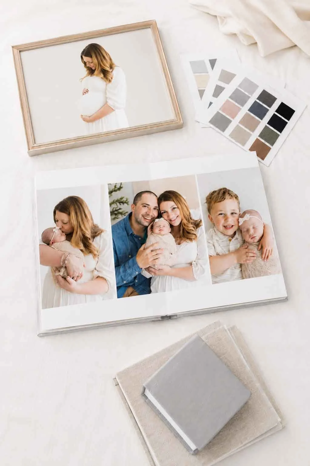 Open photo album with family pictures, color swatches, and fabric swatches on a white surface.