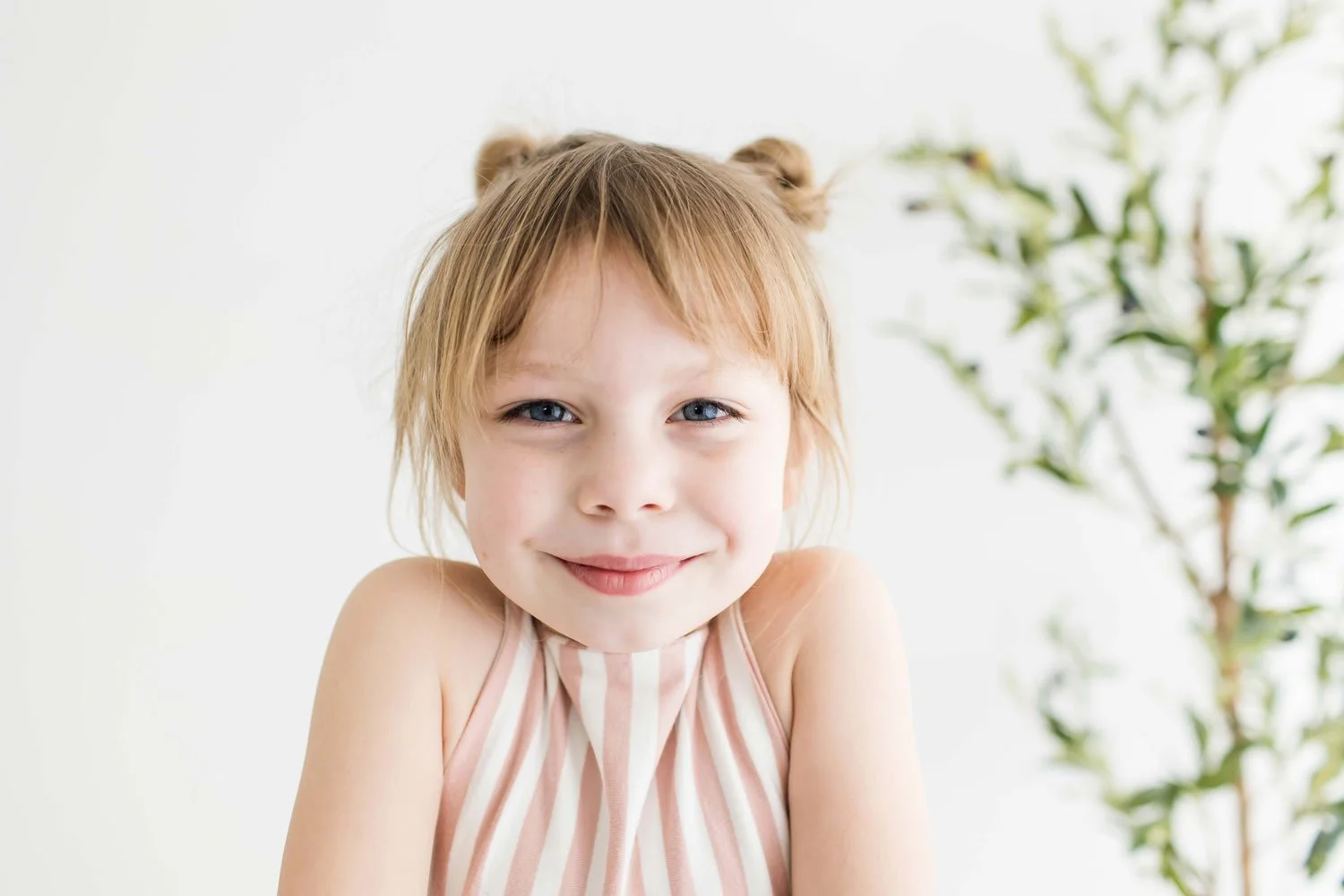A young girl with red hair styled in two buns at East and Elm Portrait Studio during an in-studio child milestone photography session in Fairport, NY.