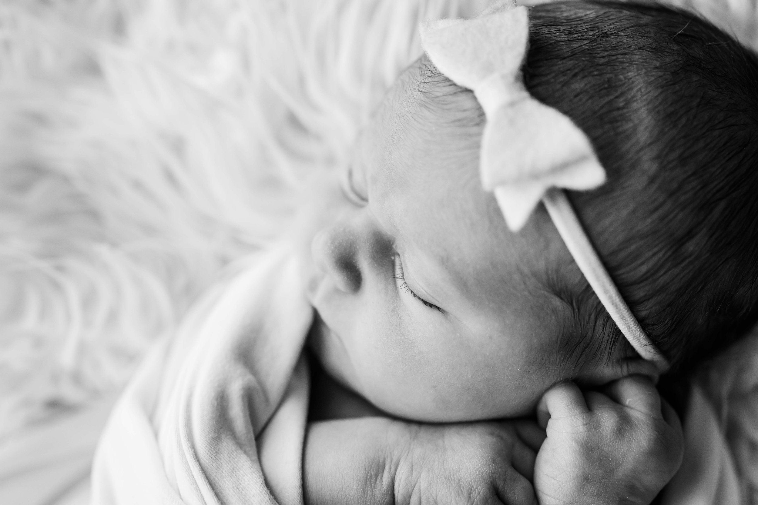 Close-up black and white photo of a sleeping baby with a pacifier, lying on a soft surface at East and Elm Portrait Studio during a newborn photography session in Fairport, NY.