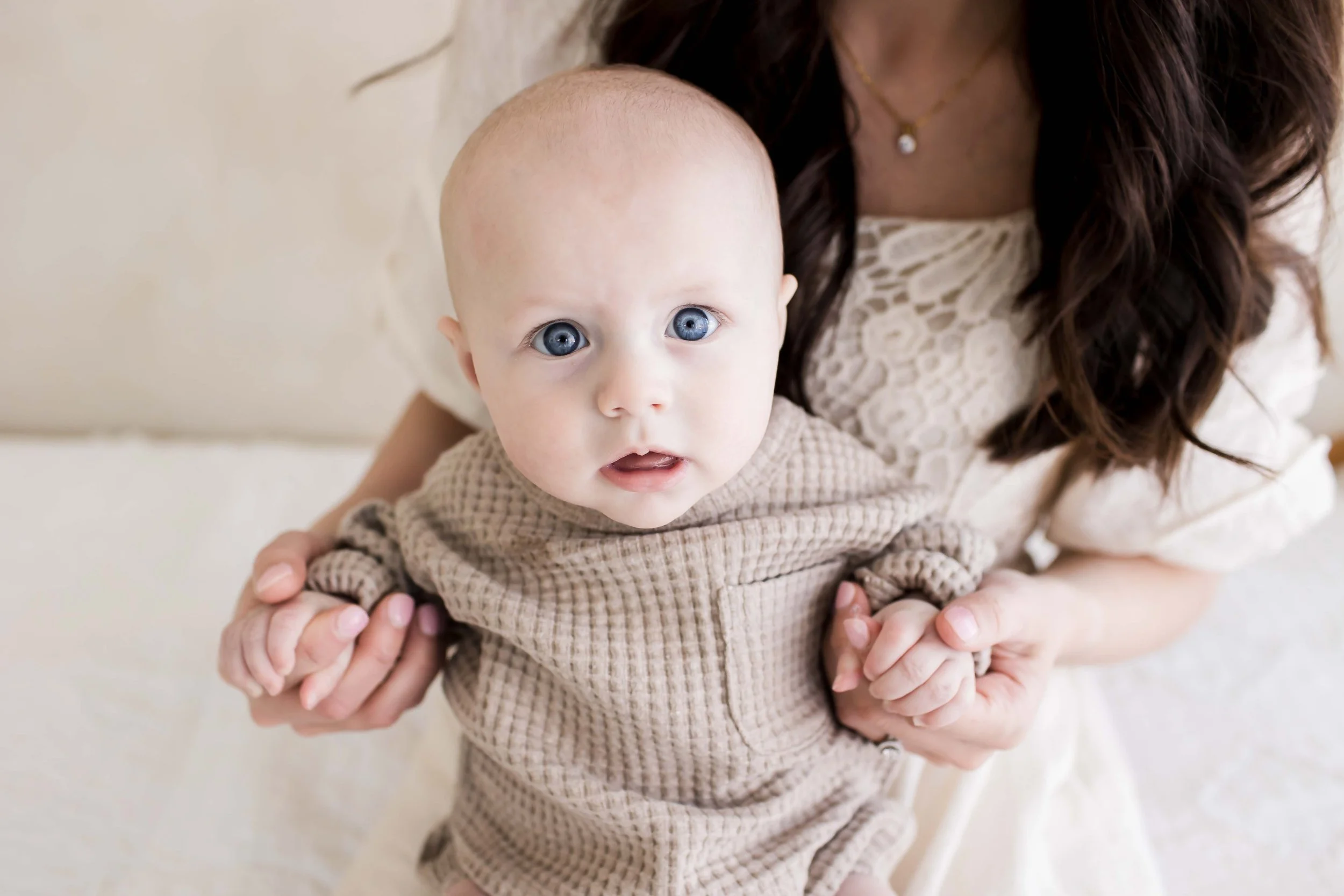 A baby being held by his mom at East and Elm Portrait Studio in Fairport, NY, during a family session.