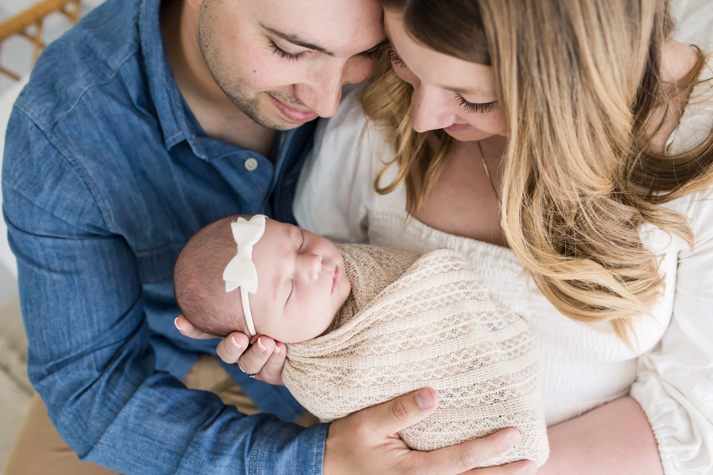 Father and mother cuddling their newborn baby indoors, Rochester NY newborn photography