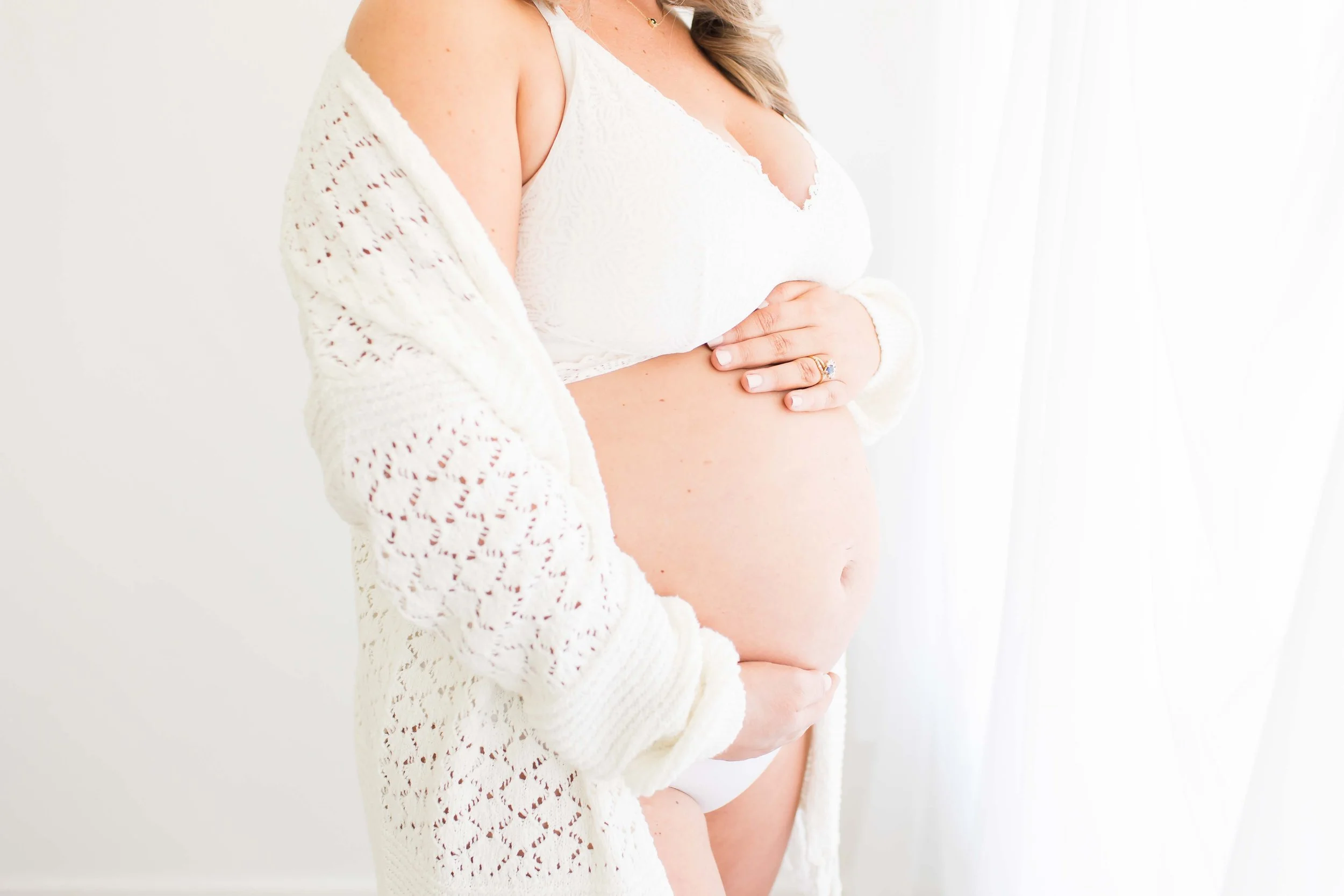 Mother looking out window holding bump at East and Elm Portrait Studio in Fairport, NY