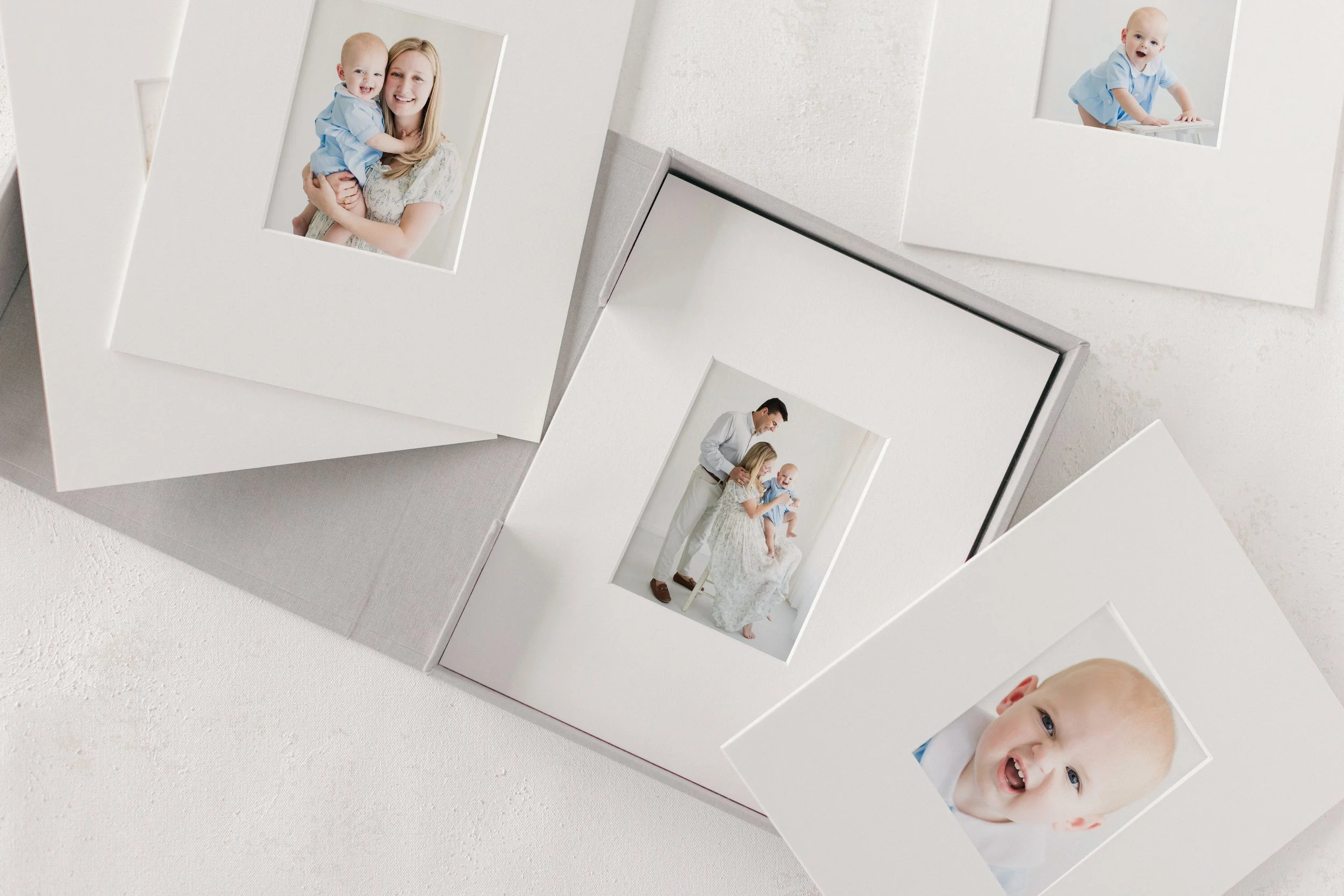 Close-up of a collage of photographs featuring a woman, a baby, and a man. The woman is holding the baby, smiling at the camera, while the baby is looking playful with a toothy smile. Additional photos show the woman and baby interacting with the man in a bright, minimalist setting.