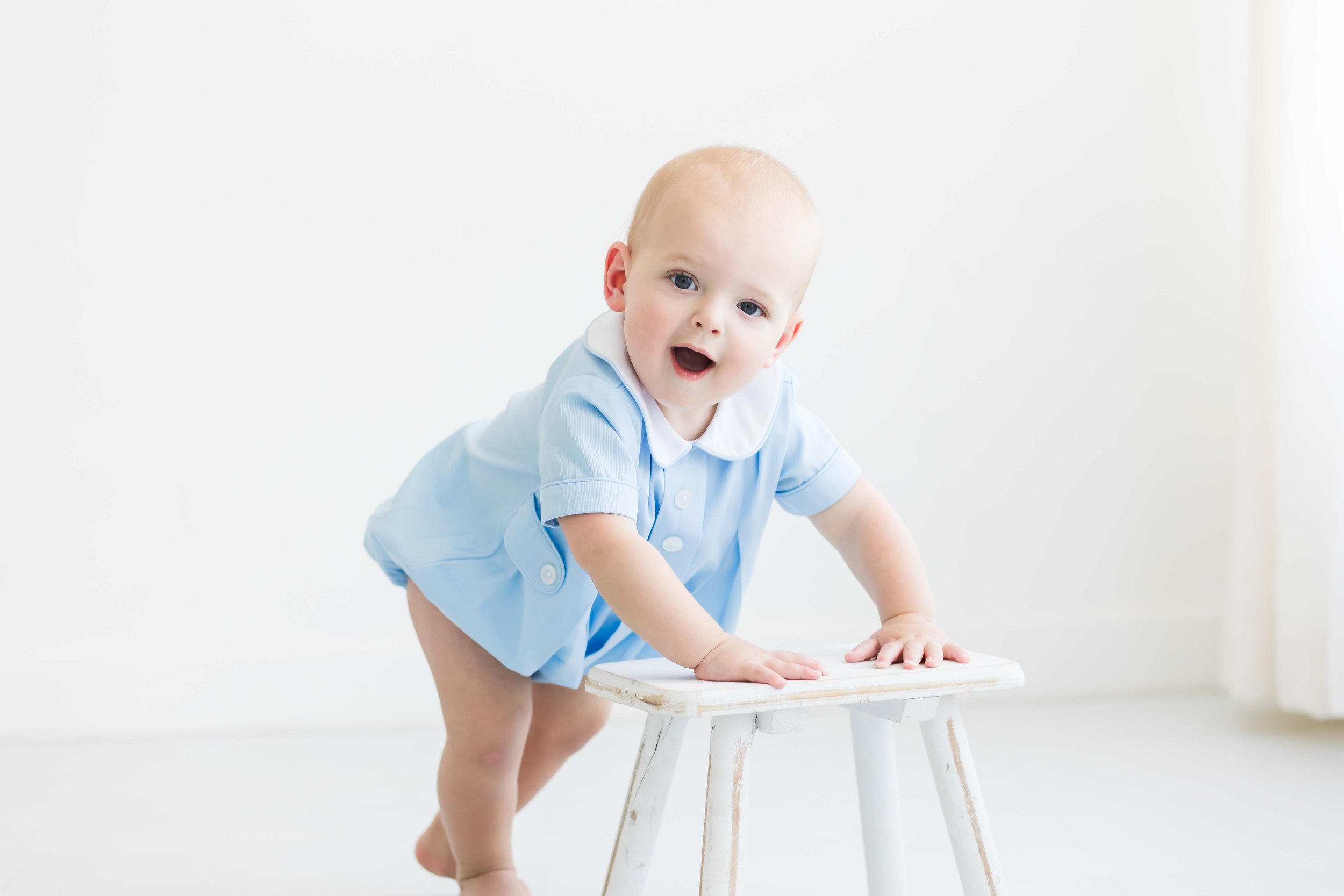 A young boy smiling with his mouth open, against a plain white background at East and Elm Portrait Studio in Fairport, NY, during a milestone session.