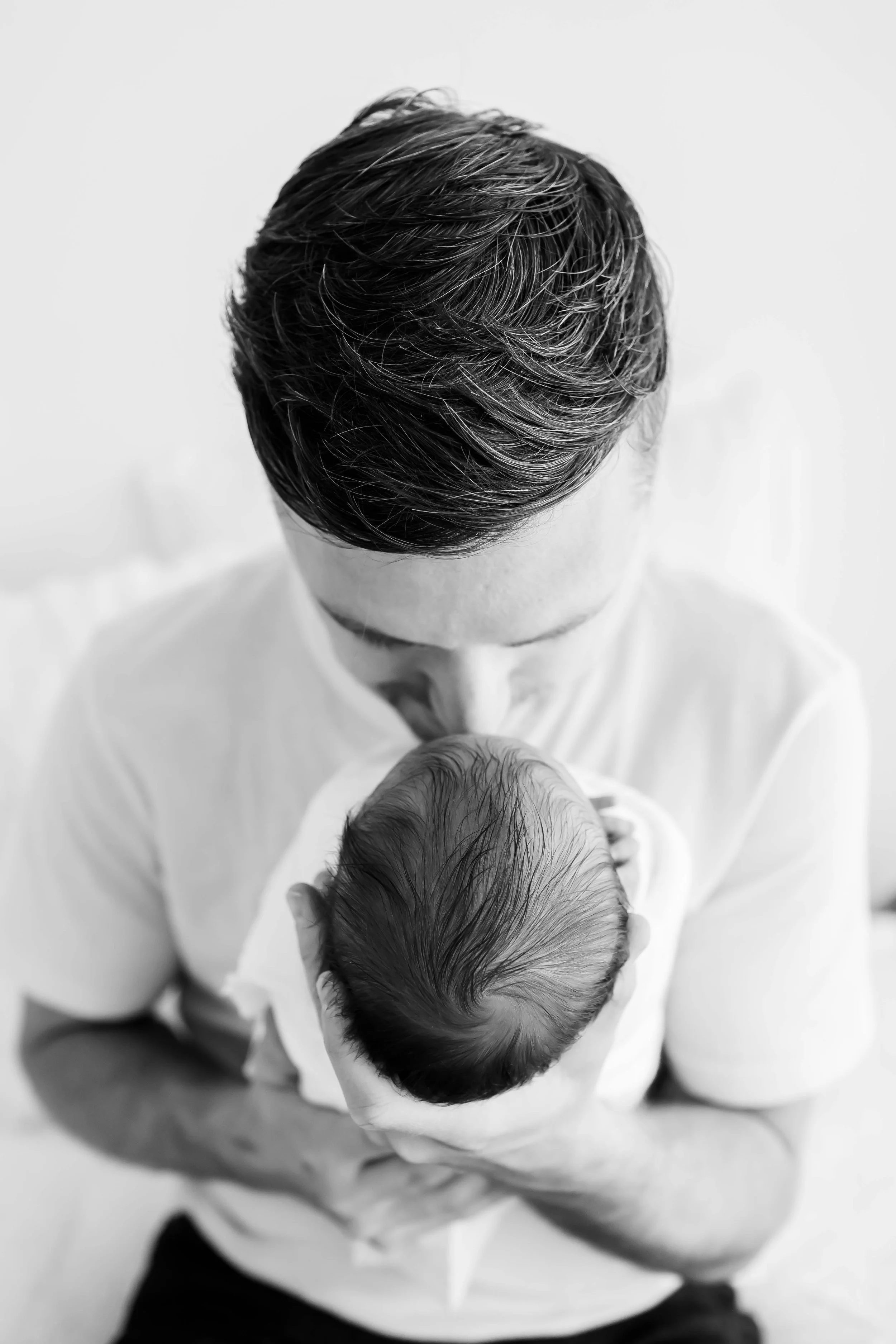 Black-and-white photo of a dad holding a newborn baby at East and Elm Portrait Studio in Fairport, NY, during a newborn session.